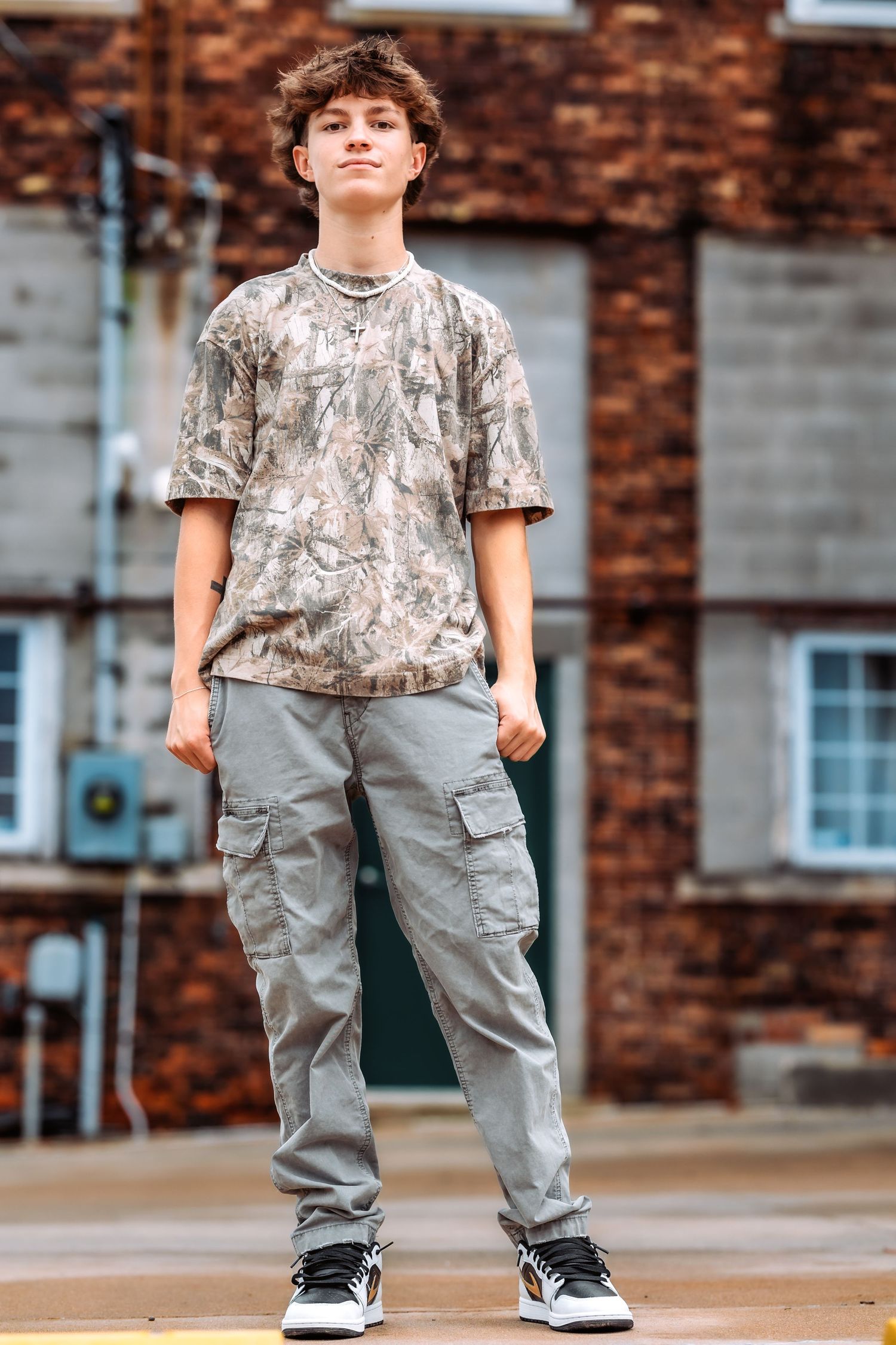 Three cropped views of someone wearing a camouflage t-shirt and baggy gray cargo pants with black sneakers.