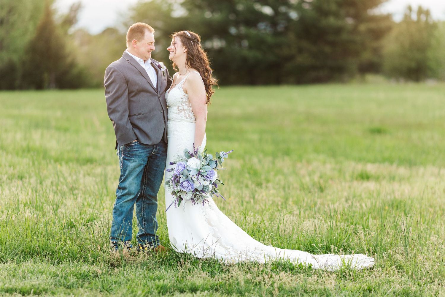 Wedding portrait session in green field with flowing white dress and natural backdrop.