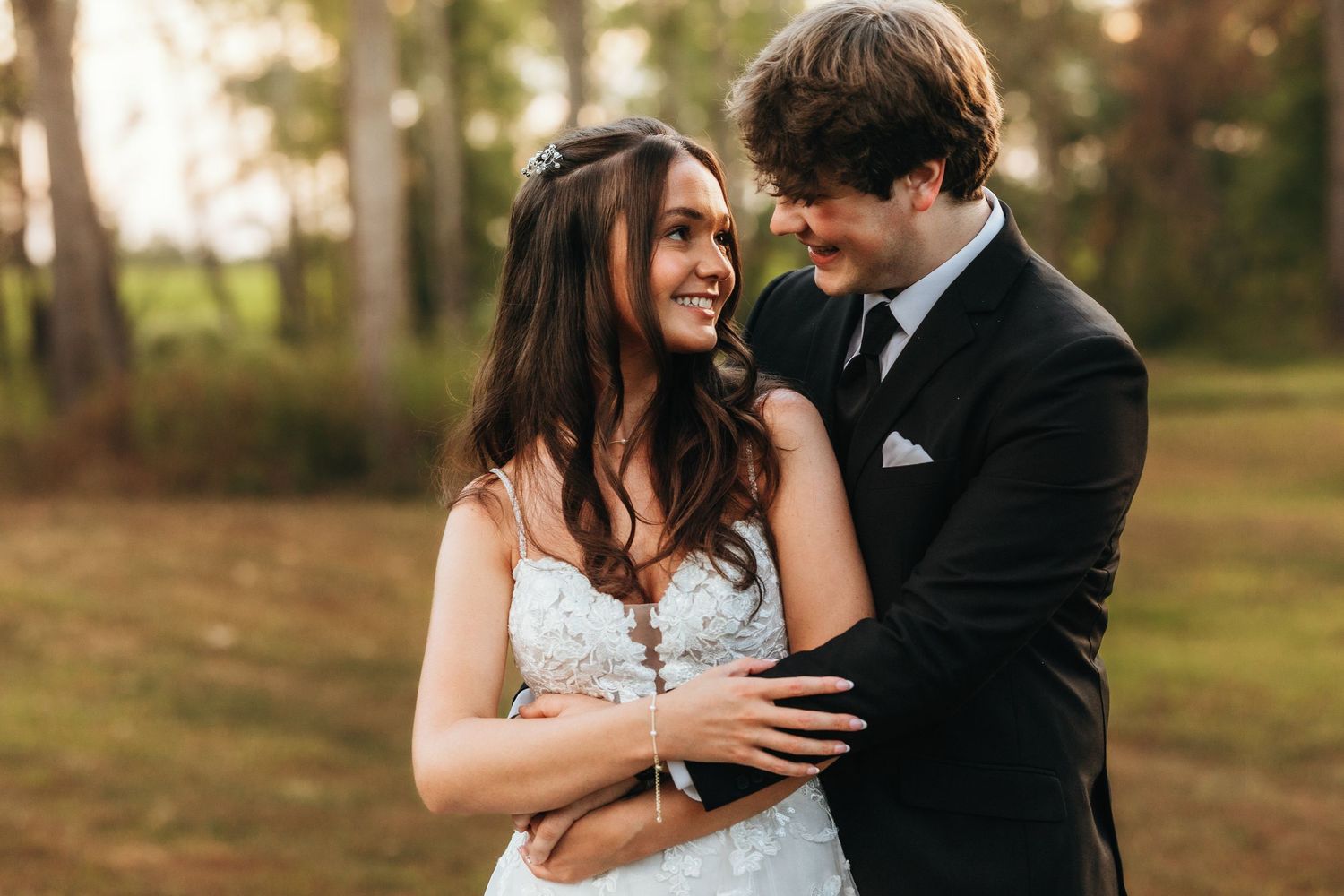 Intimate wedding portrait of couple sharing a tender moment in formal attire outdoors.