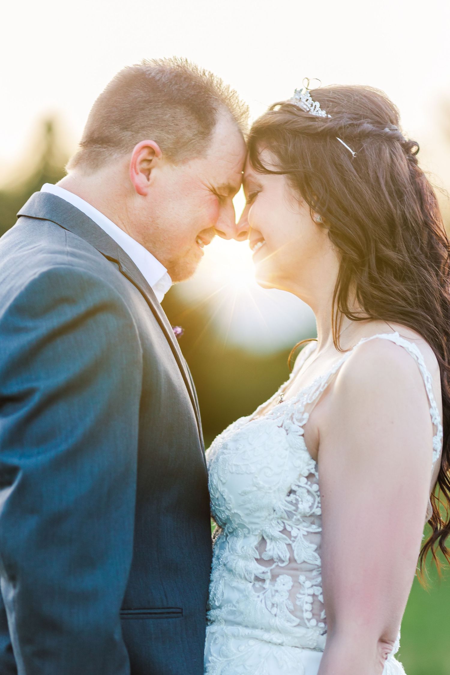 Intimate sunset portrait of newlyweds sharing a romantic moment outdoors.