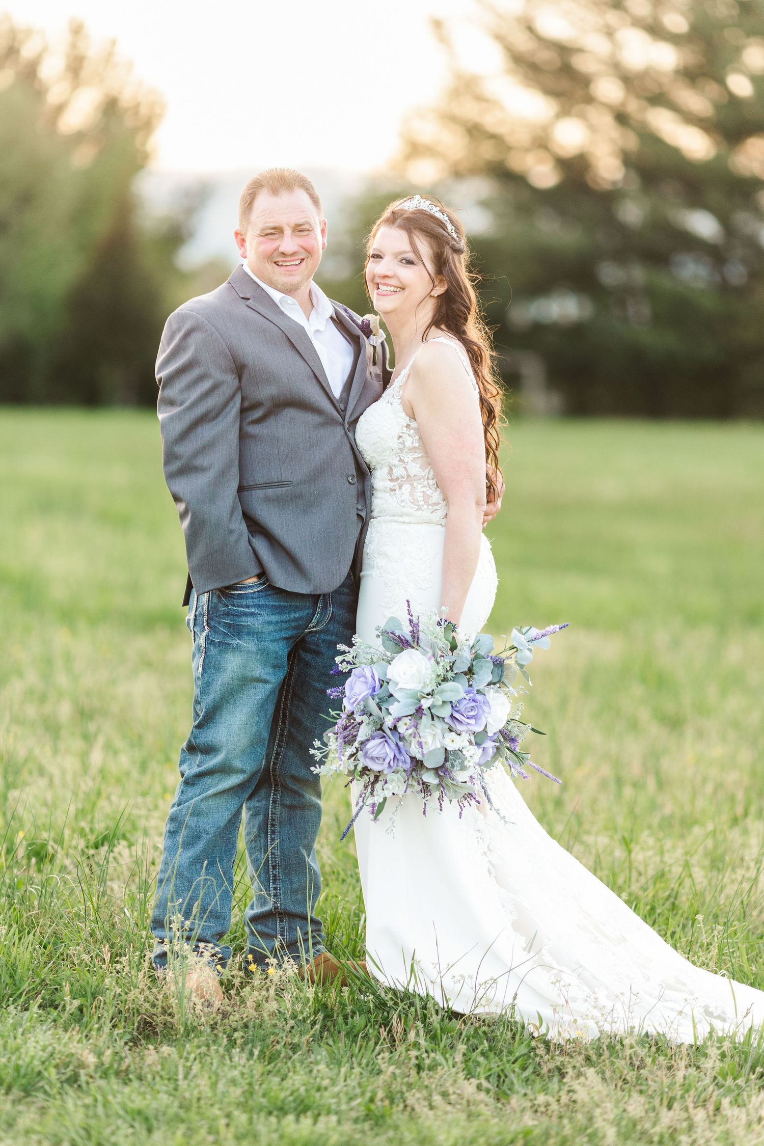 Wedding couple embraces in golden sunlit field during outdoor photo session.