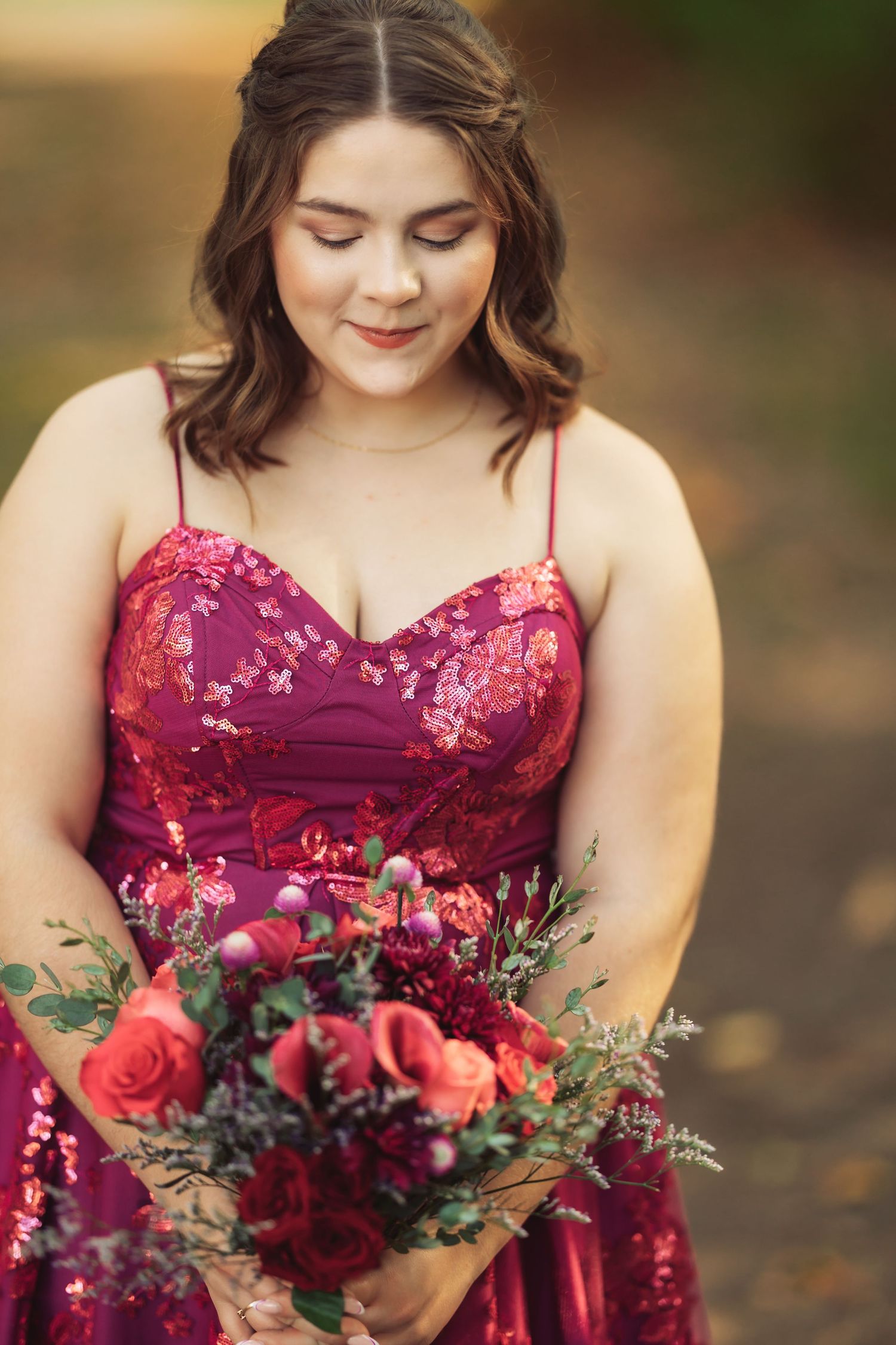 Beautiful burgundy floral dress with matching rose bouquet photographed outdoors.