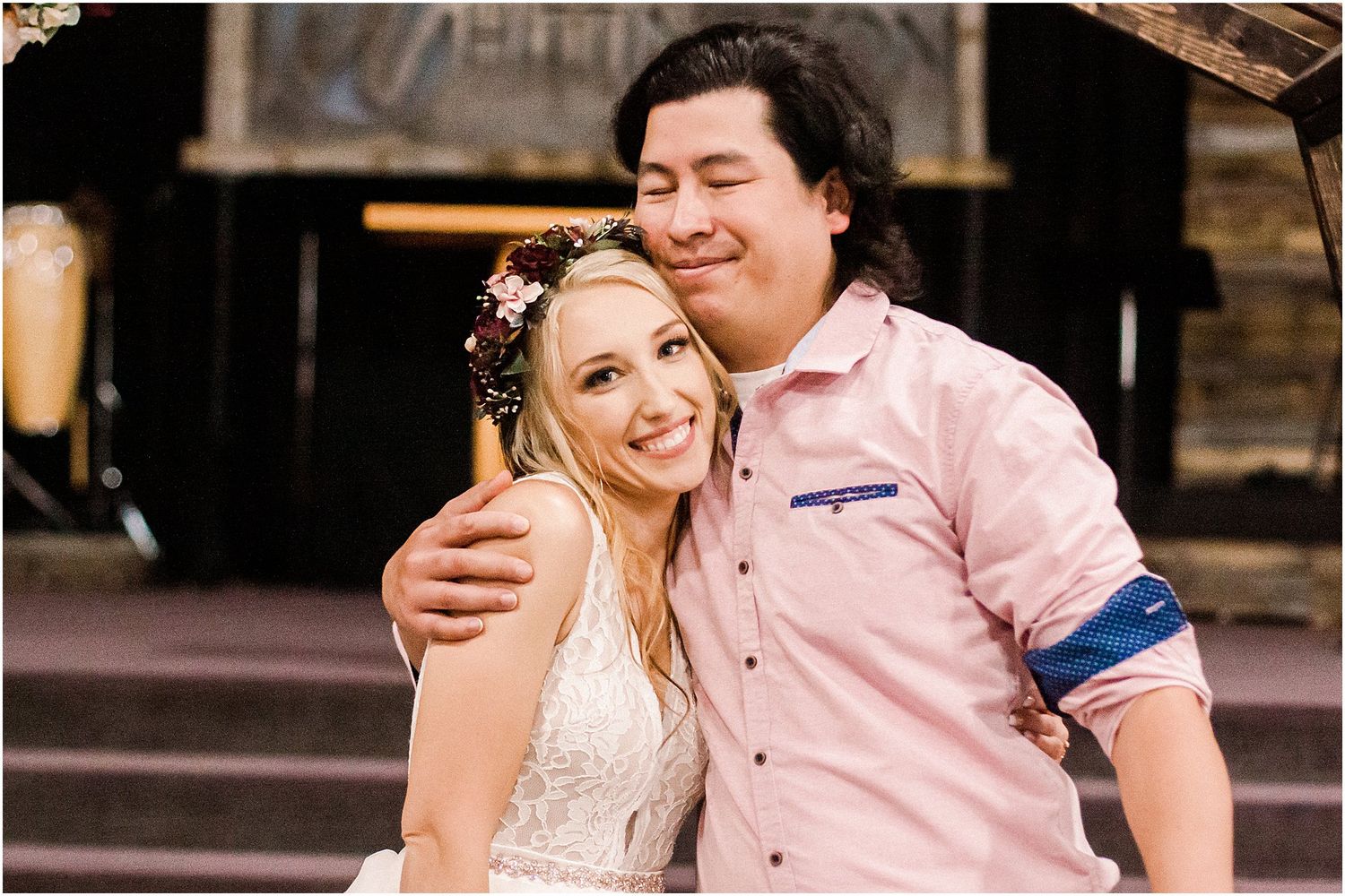 A joyful couple embraces and smiles at a rustic outdoor wedding venue.