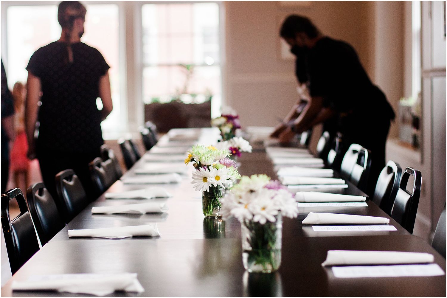 An elegant table setting with white linens and floral centerpieces at a wedding reception.