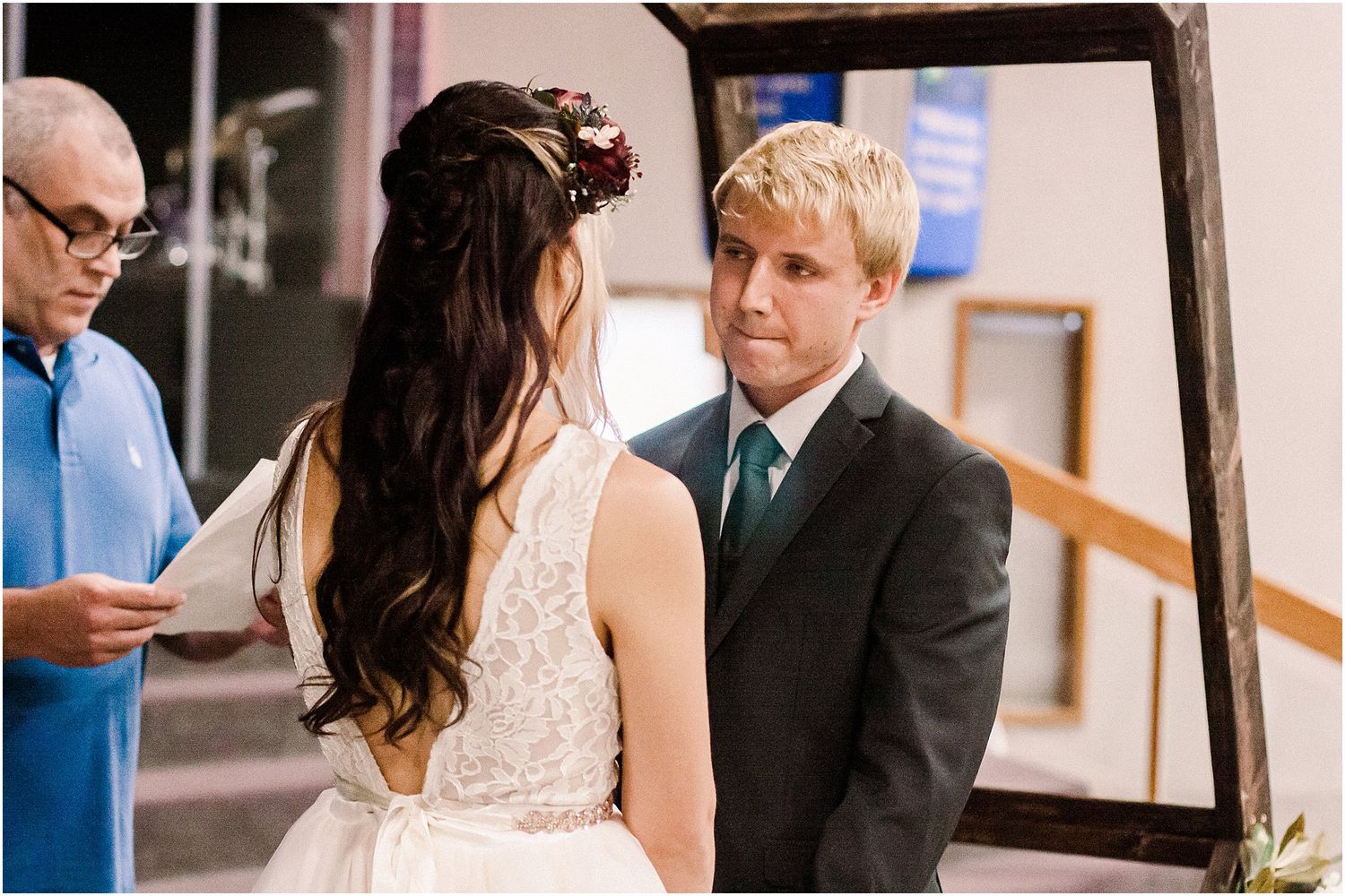Wedding ceremony preparation with couple and officiant in casual blue shirt.