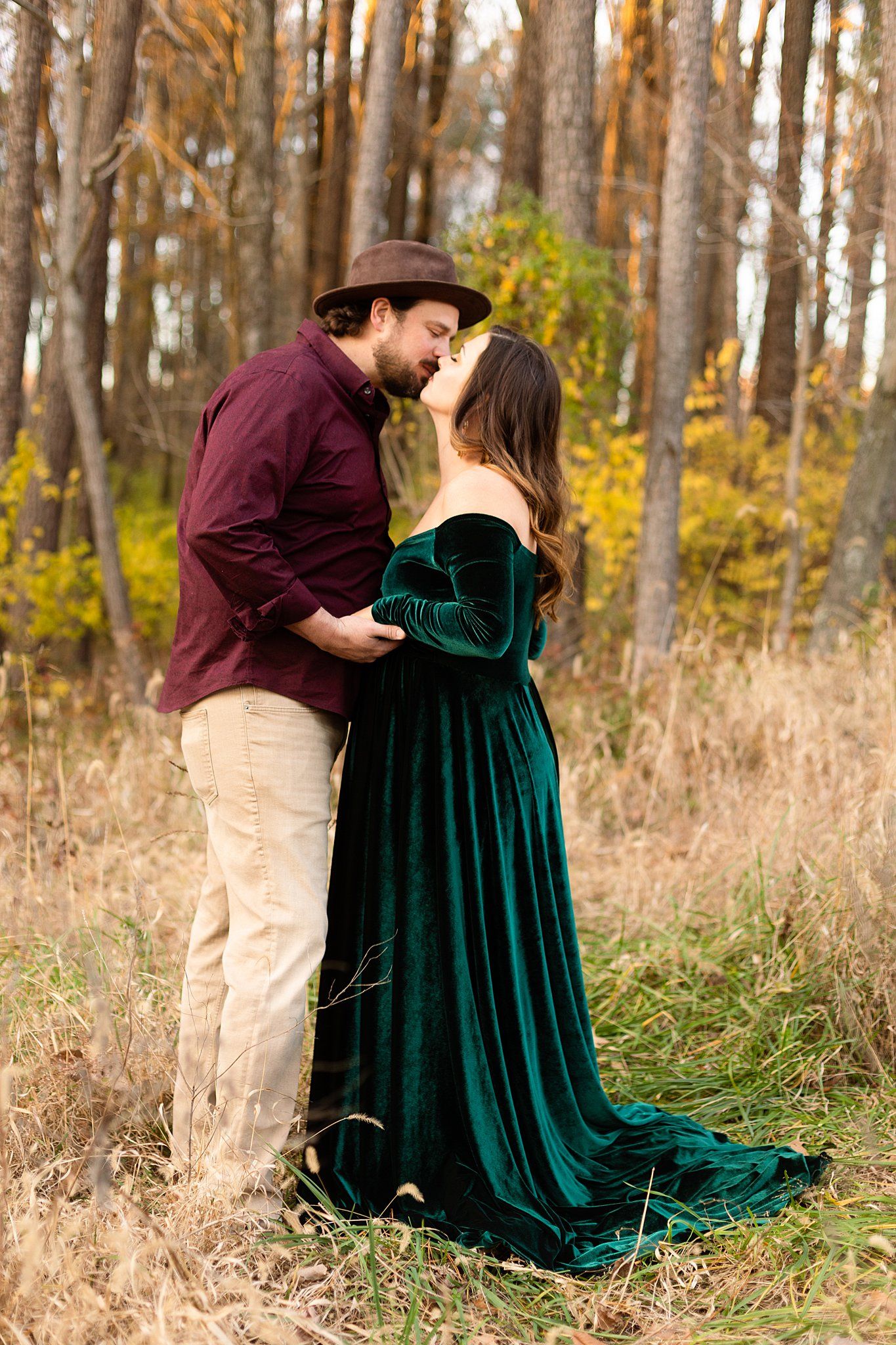 Tender moment between couple in casual formal wear against autumn forest backdrop.