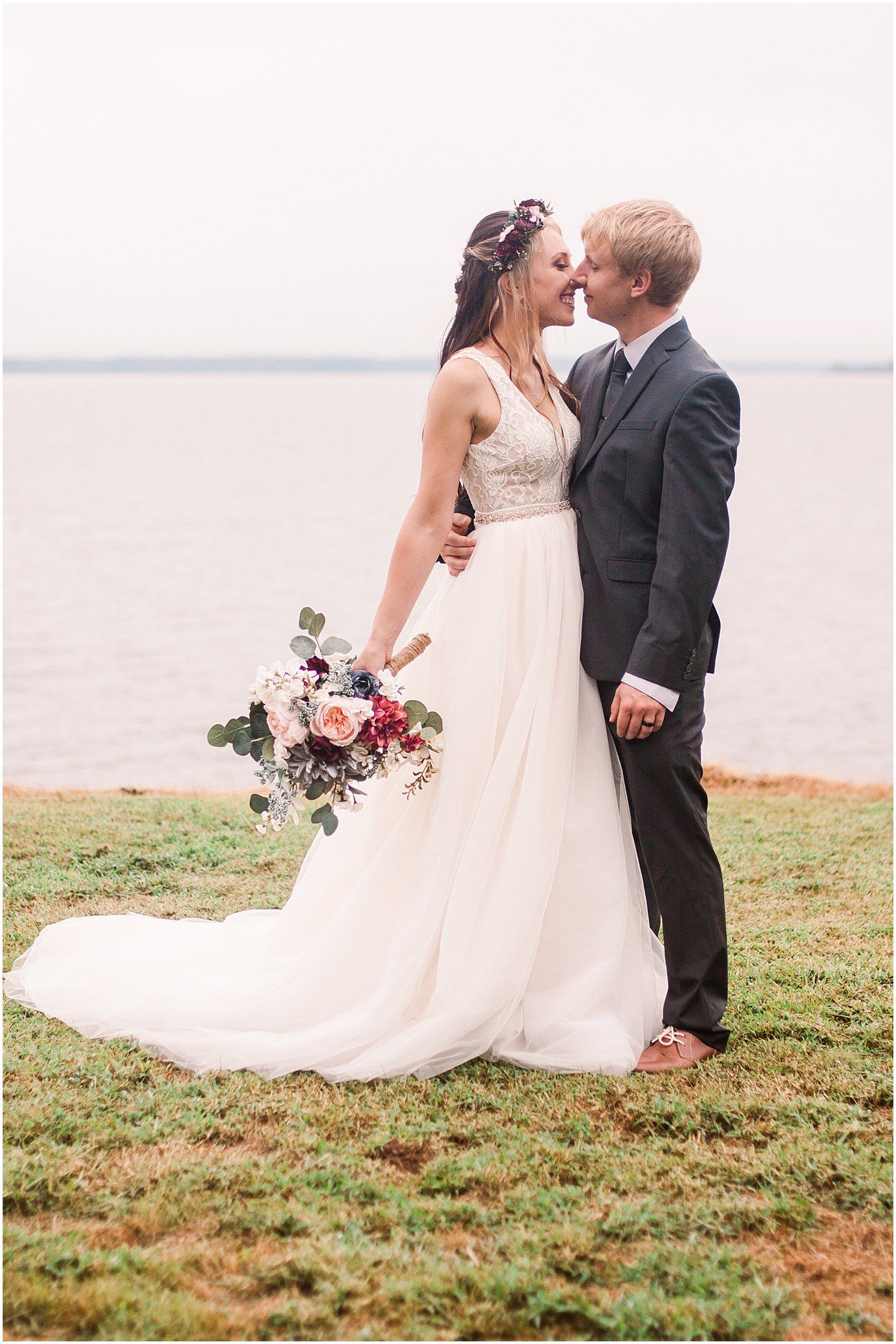 Couple shares intimate moment by the water during wedding photoshoot.
