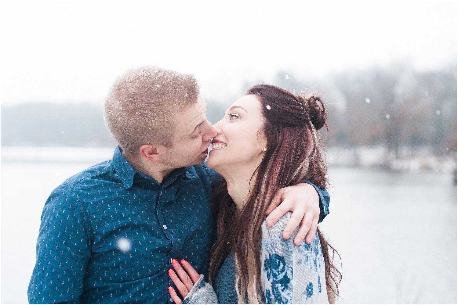 An intimate winter moment captured with snowflakes falling around the couple.