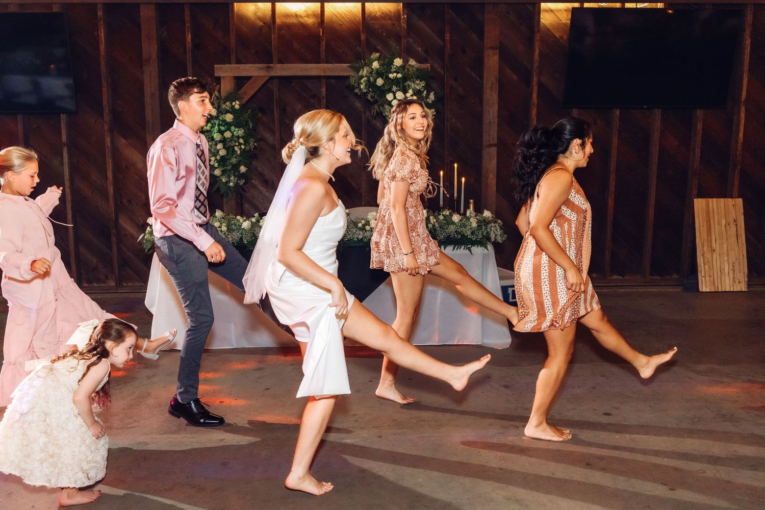 Couples dancing together on a wooden dance floor at an evening wedding reception.