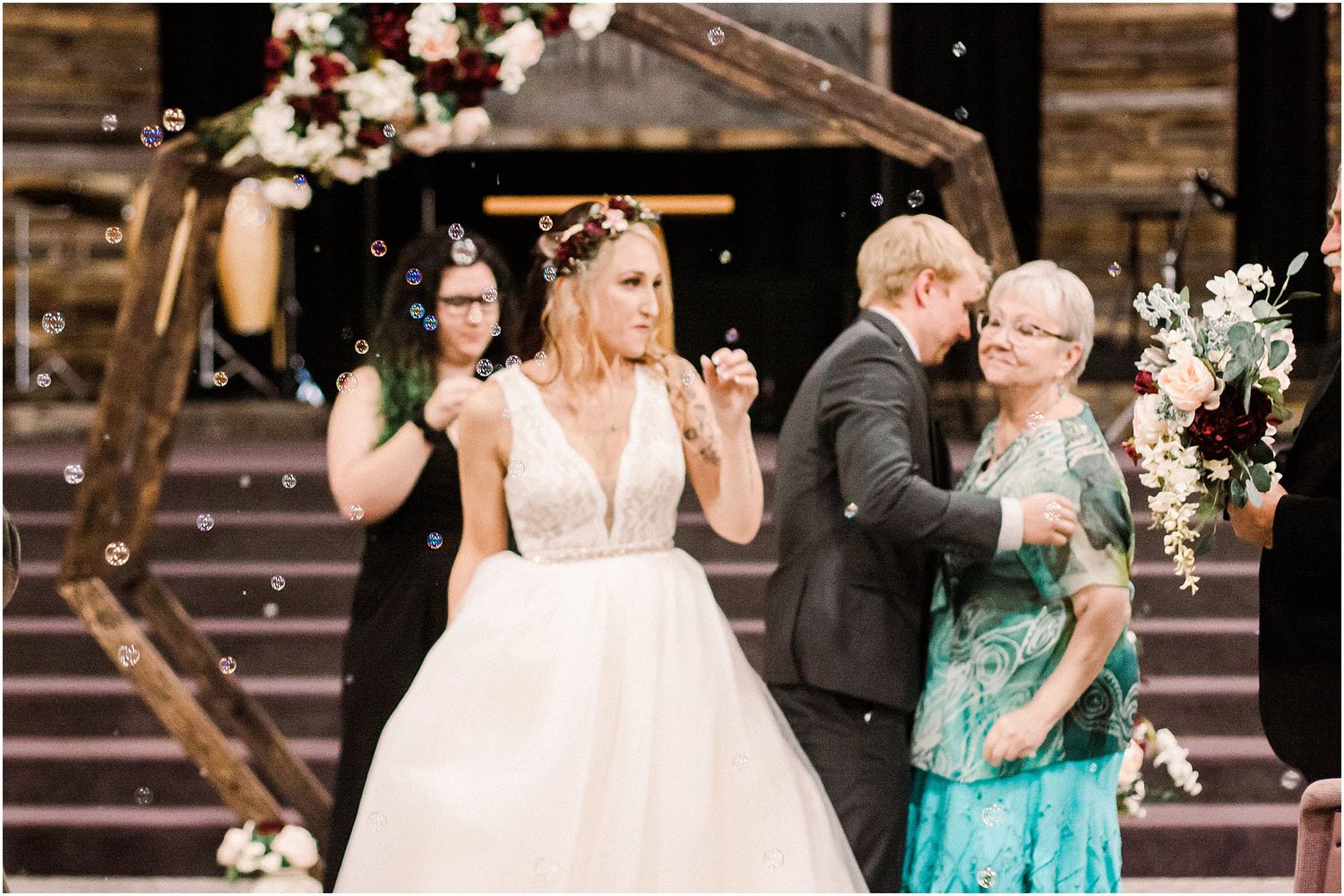 Celebratory moment at a wedding with guests and the bride in a white gown near floral decorated steps.