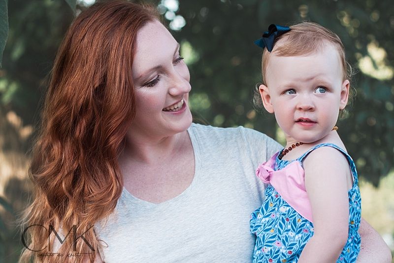 Sweet candid moment between parent and toddler wearing a blue and pink dress outdoors.