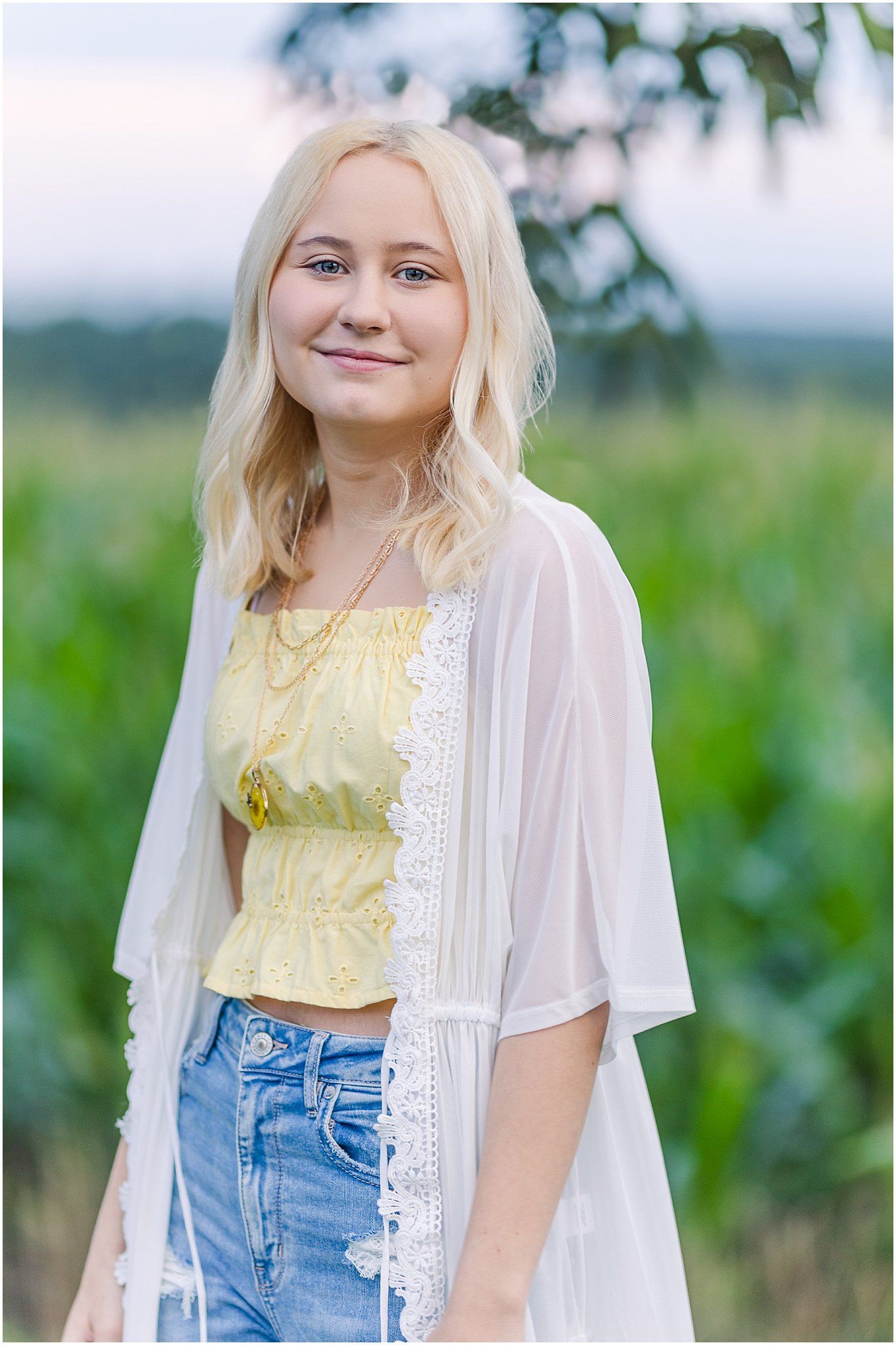 Senior girl in front of a corn field at sunset