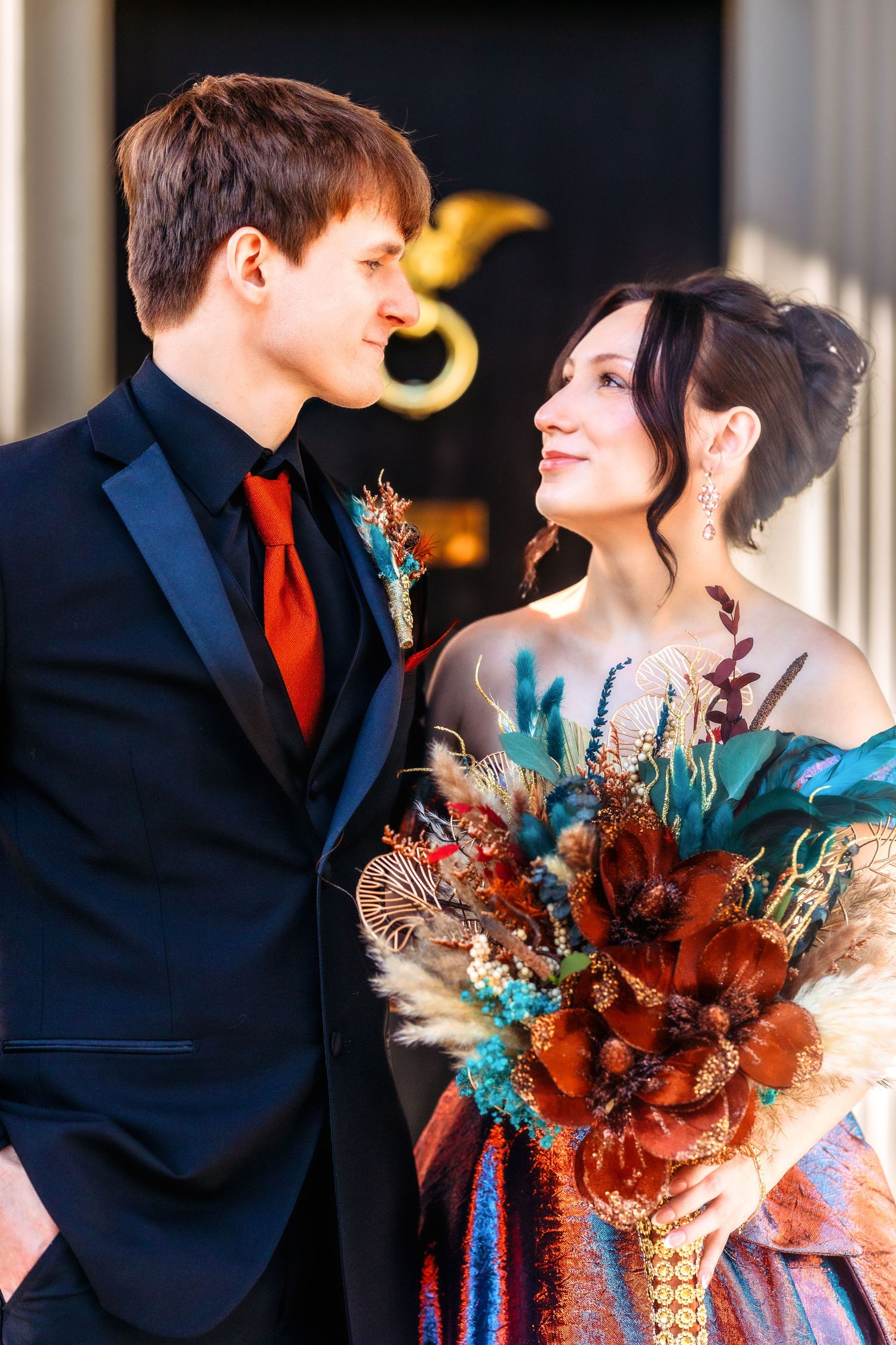 A romantic wedding couple in navy and teal with autumn-colored florals share intimate moments in a photo series.