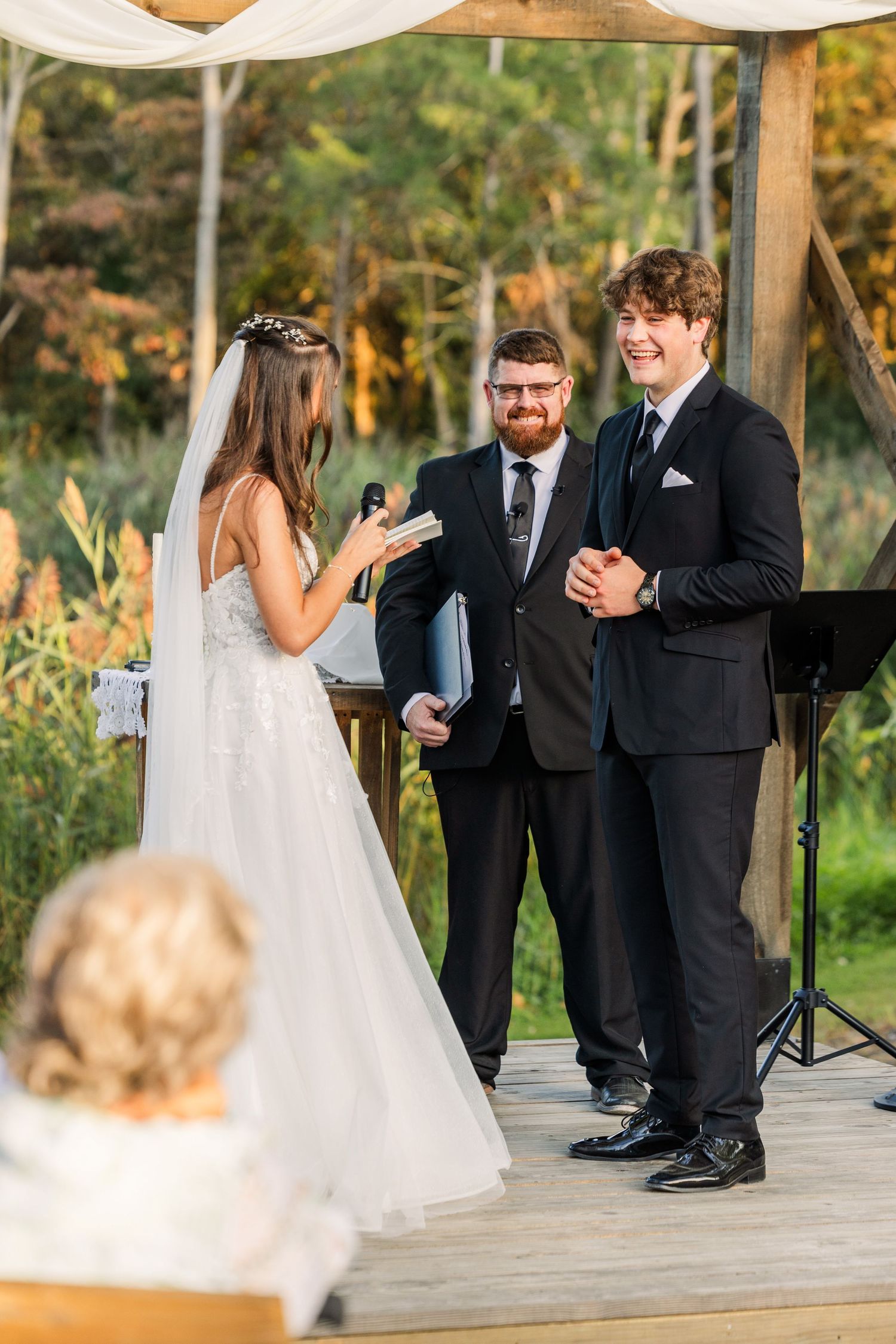 Wedding party gathered on wooden deck during outdoor ceremony.