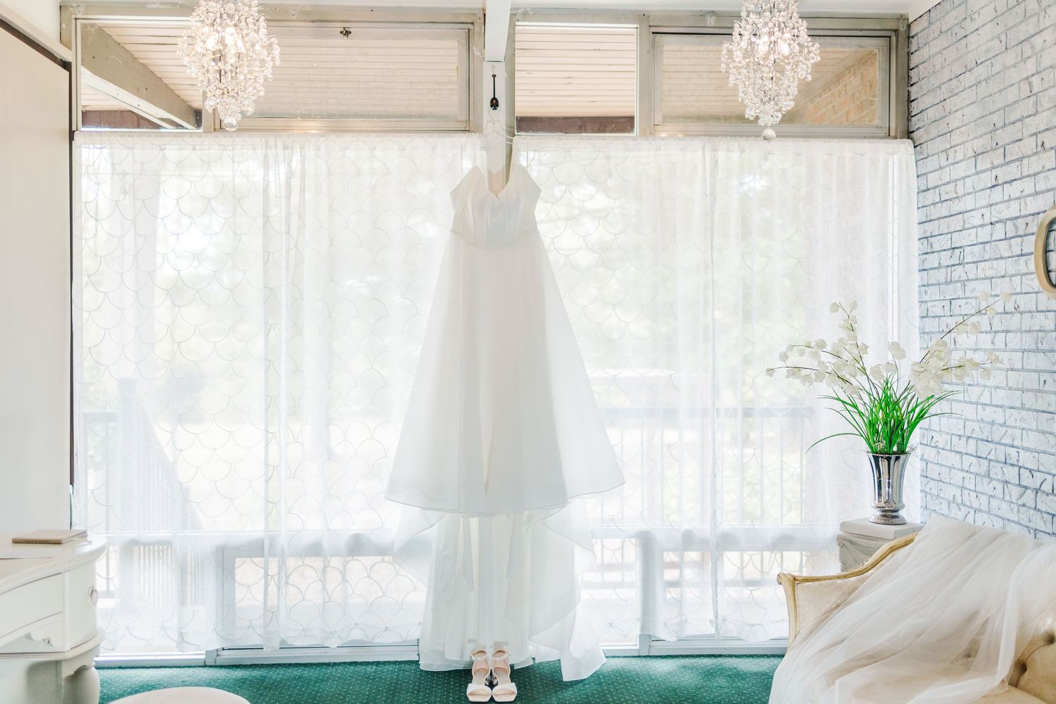 Modern white wedding venue interior with crystal chandeliers and draped fabric decor.