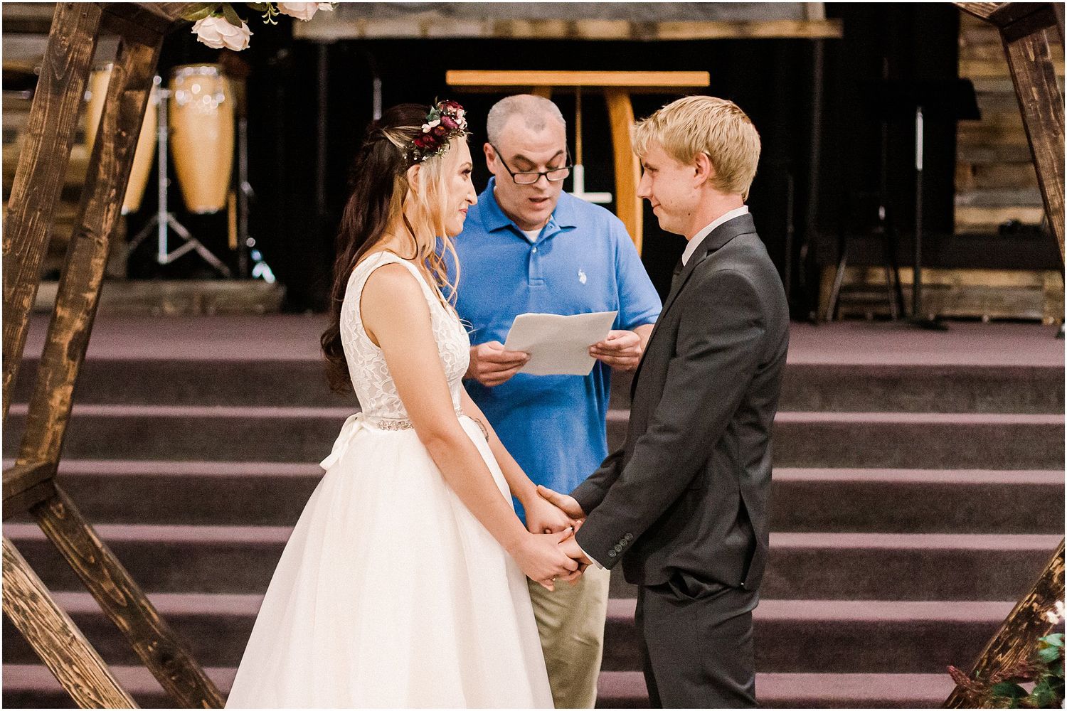 An intimate wedding ceremony takes place on stairs with a rustic arch and floral arrangements.