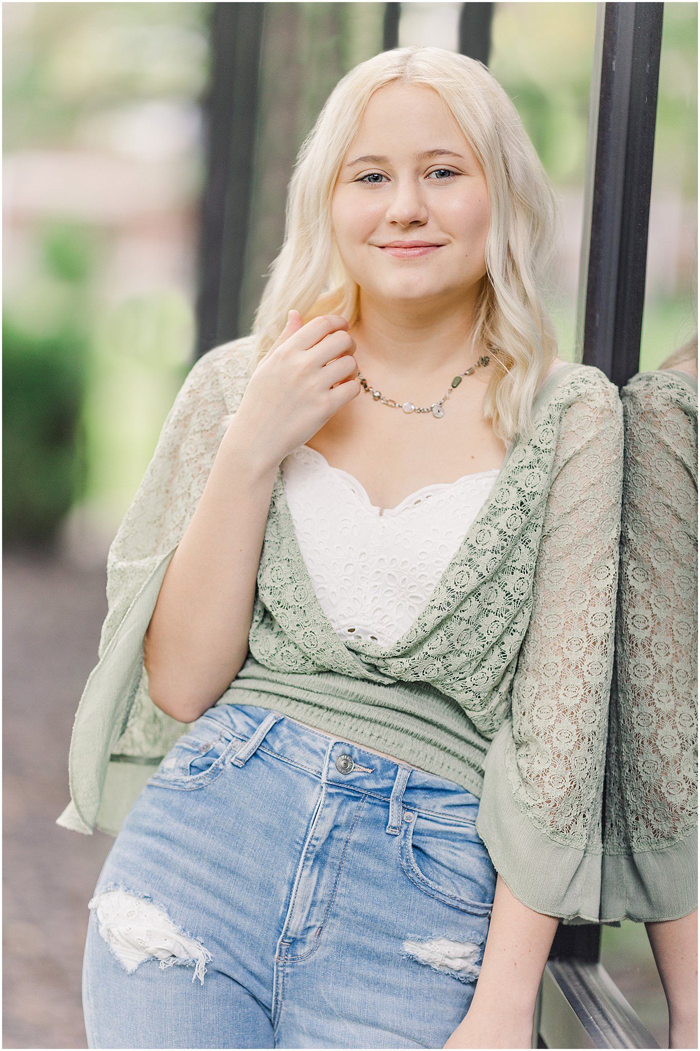 Senior girl leans against black reflective windows