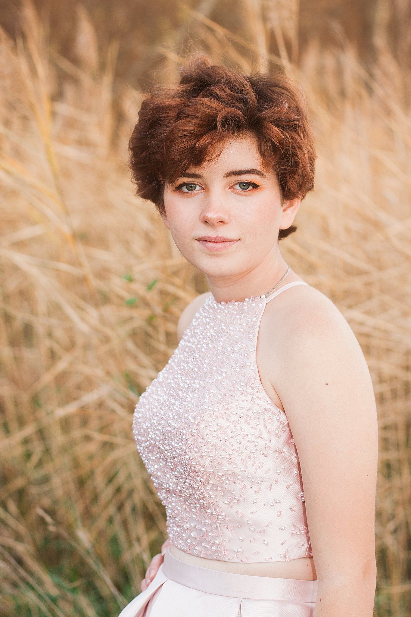 Portrait in beaded halter dress against backdrop of golden wheat field.
