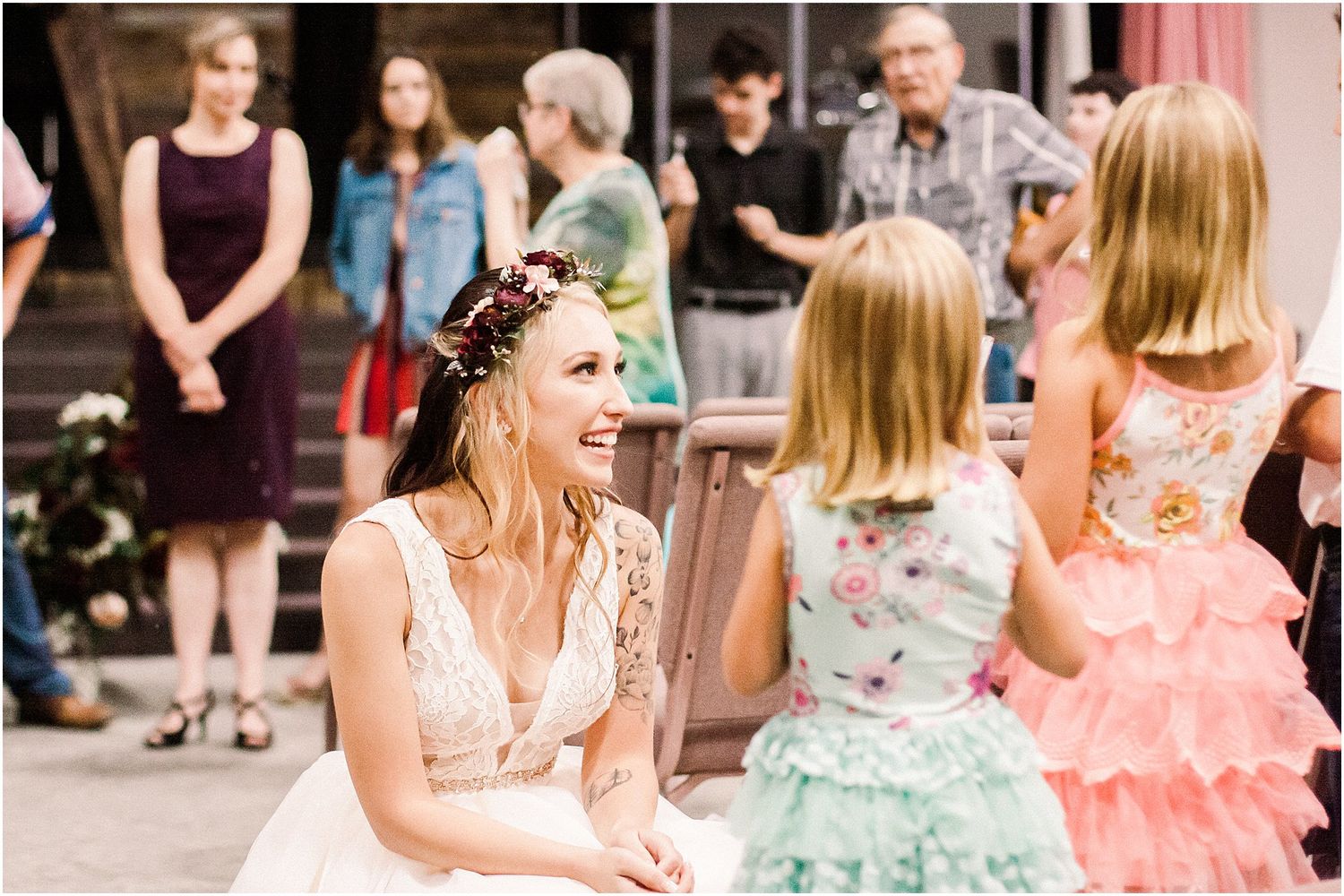 Joyful bride in lace dress interacting with guests during wedding reception.