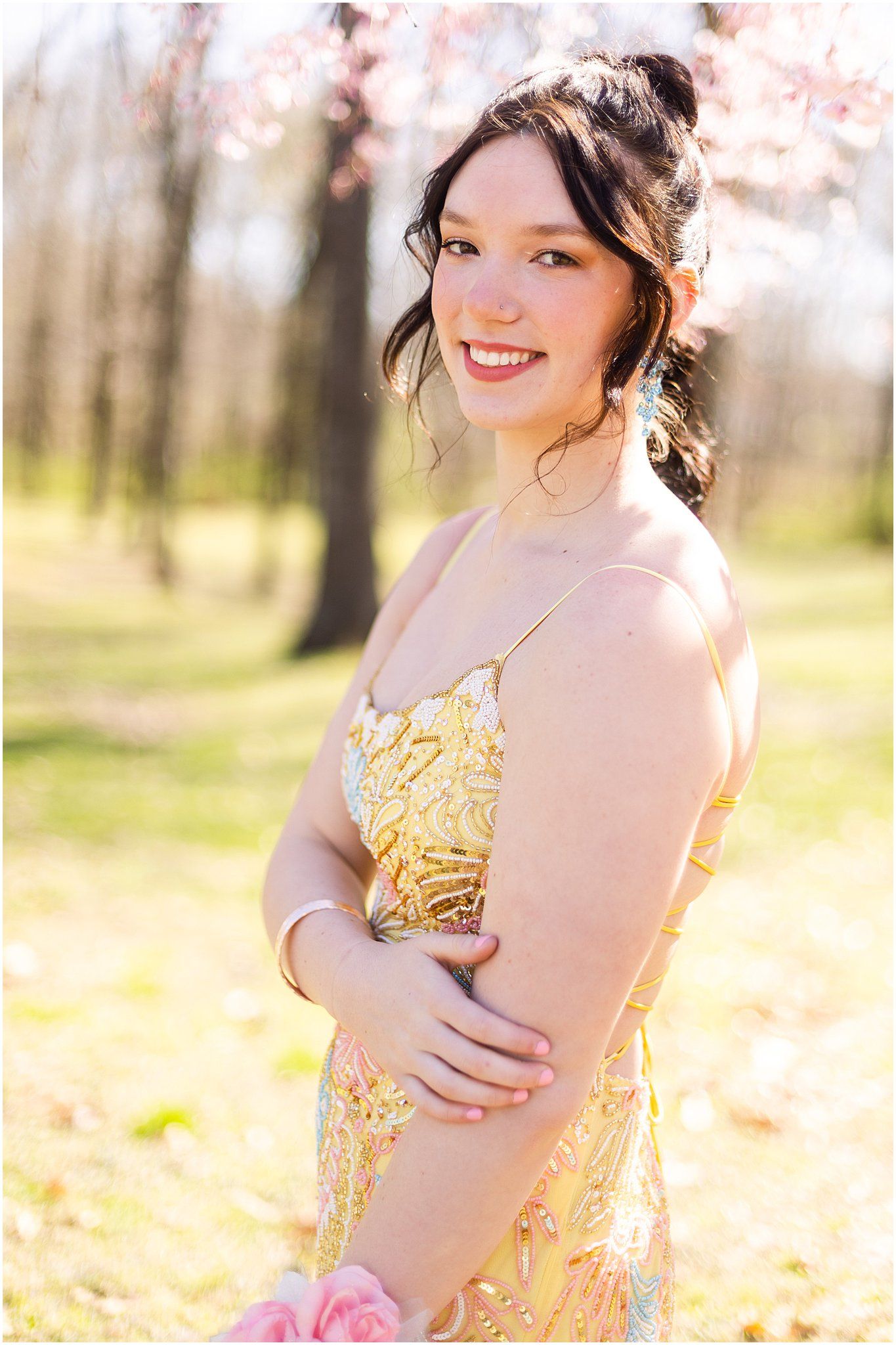 Side profile portrait in yellow formal dress with spring blossoms in background.