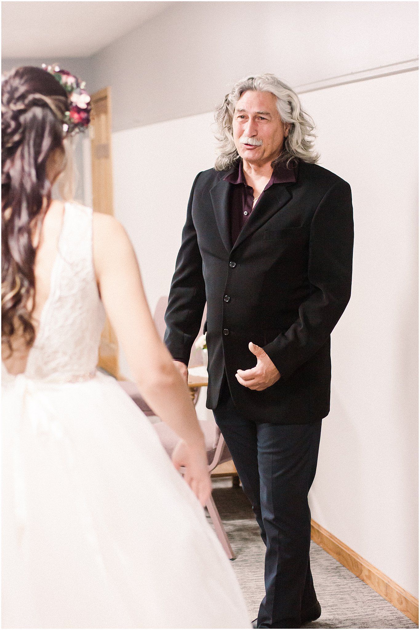 A wedding first look moment captured in a simple indoor hallway with wooden doors.