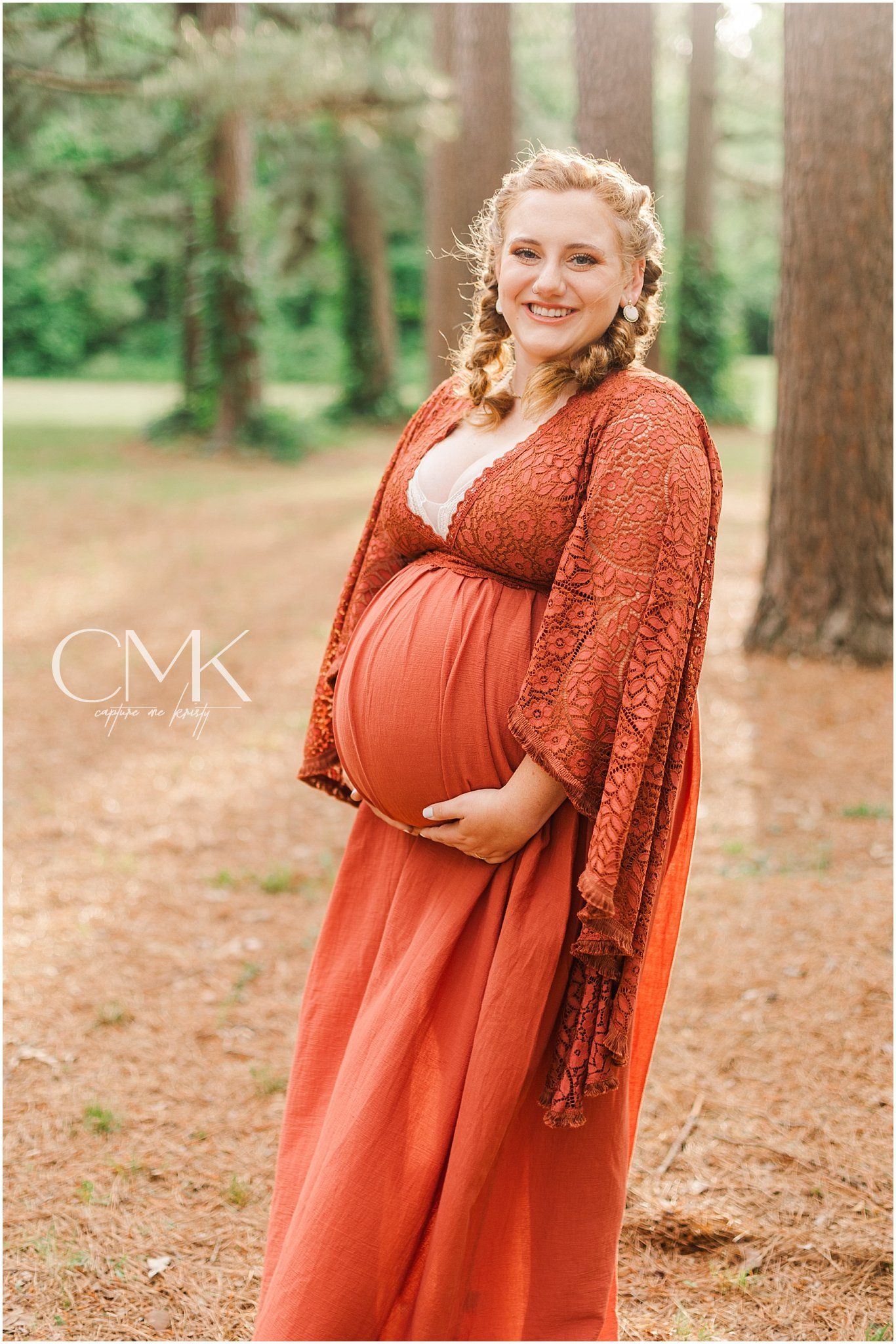 Beautiful maternity photograph showcasing a rust-colored lace and maxi dress combination in a forest.