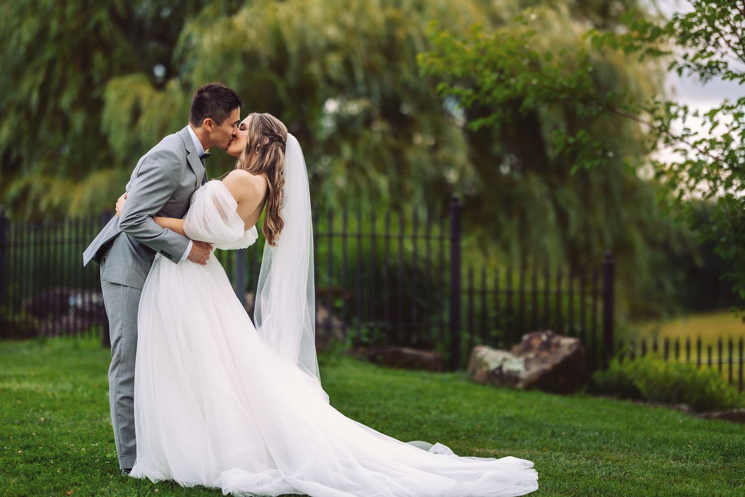 A romantic wedding portrait with a flowing veil against a lush garden backdrop.