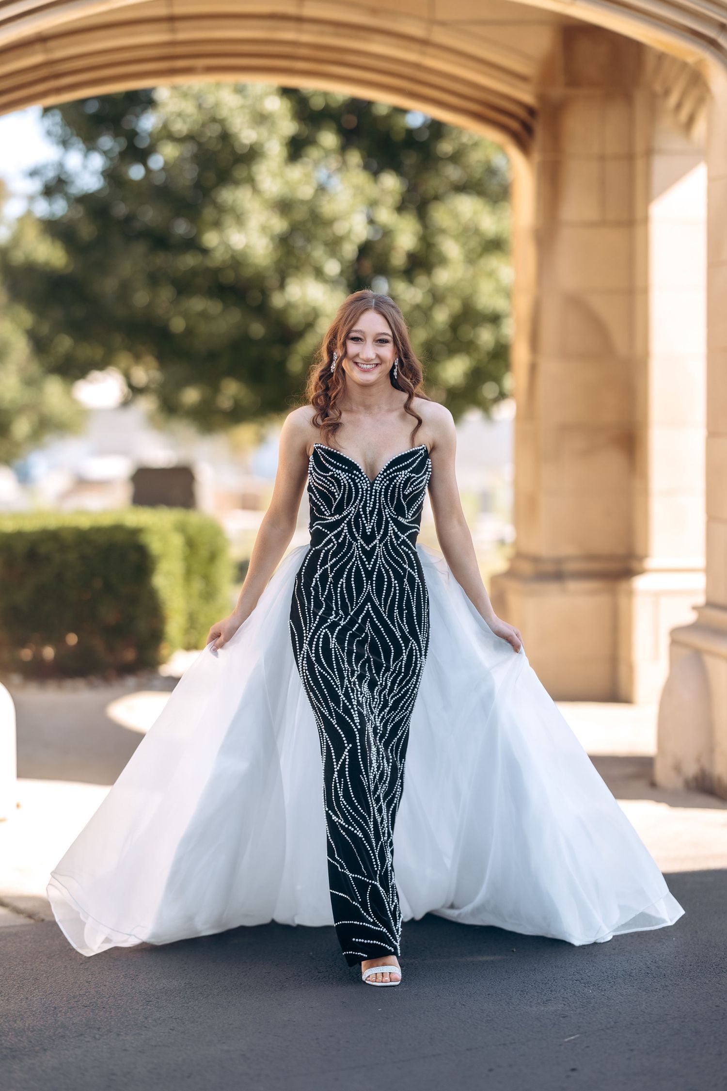 A dramatic black and white formal dress photographed under stone arches.