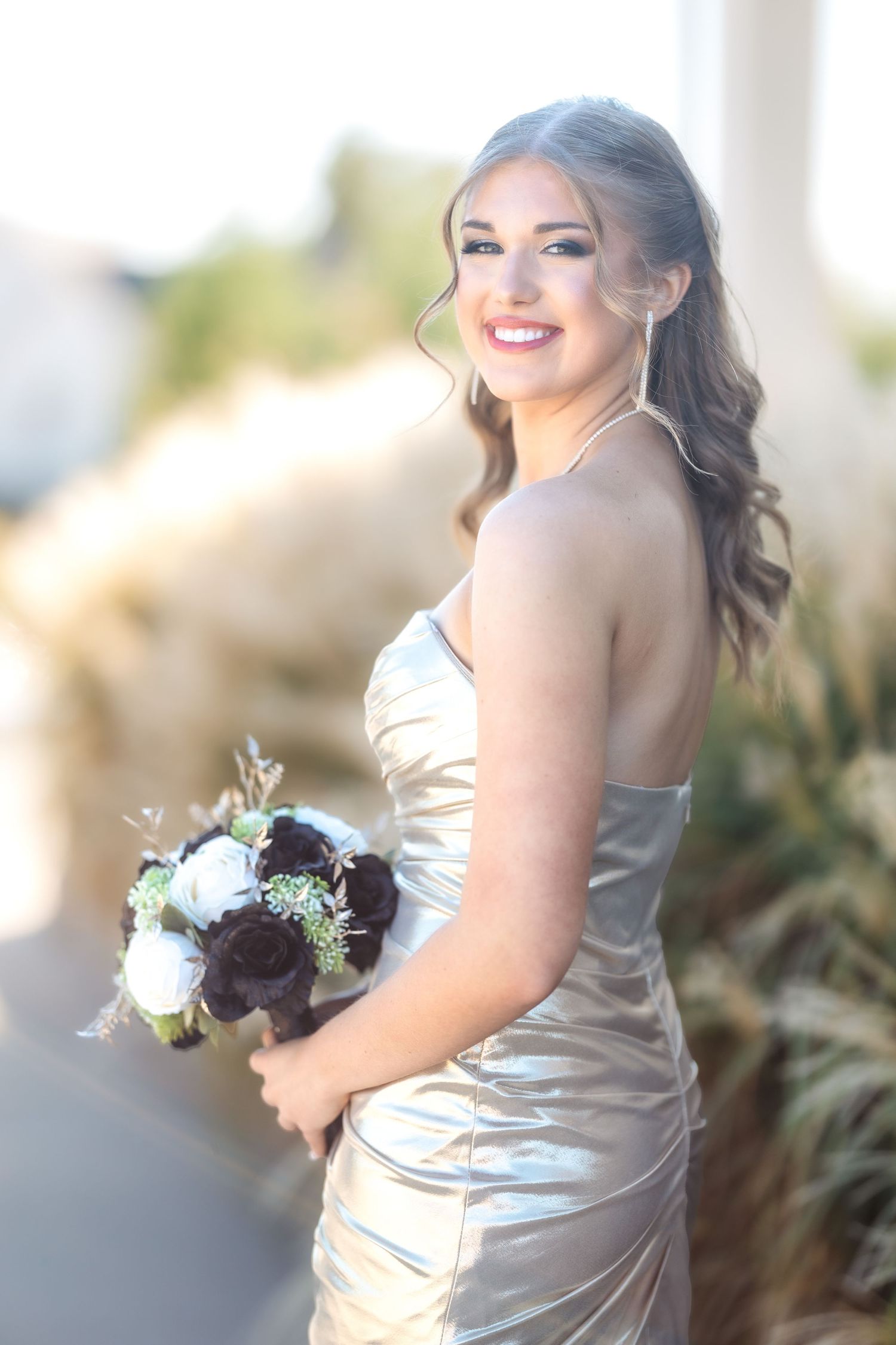 Elegant silver satin dress with floral bouquet captured in soft natural lighting.