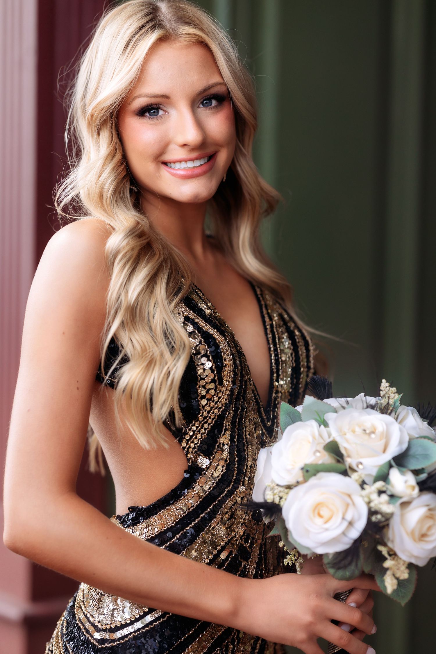 Elegant beaded black dress with white floral bouquet photographed against dark background.
