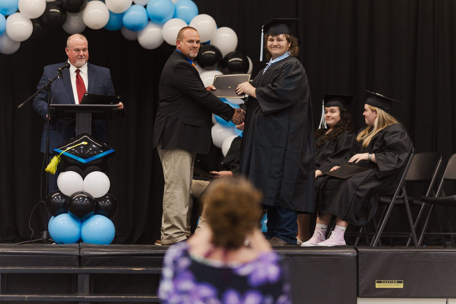 Graduation ceremony venue decorated with blue and white balloons and chairs arranged in rows.