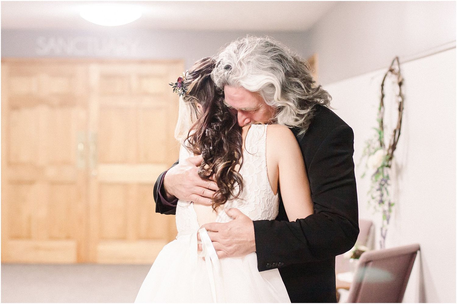 A tender embrace during a wedding first look with soft indoor lighting.