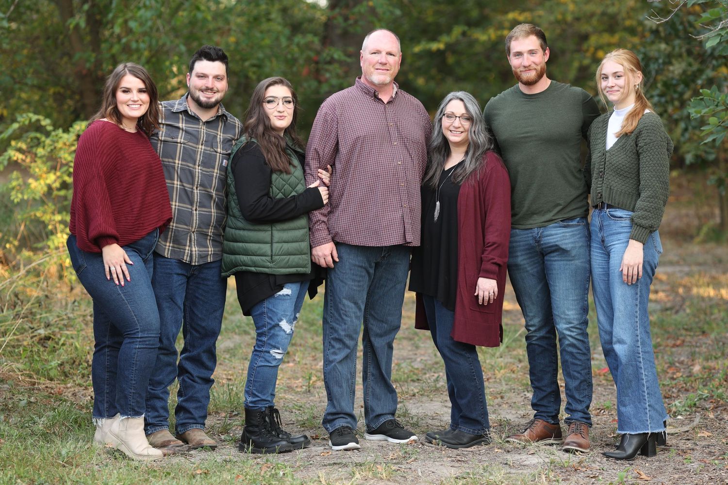 Family group photo in casual attire posed outdoors during autumn.