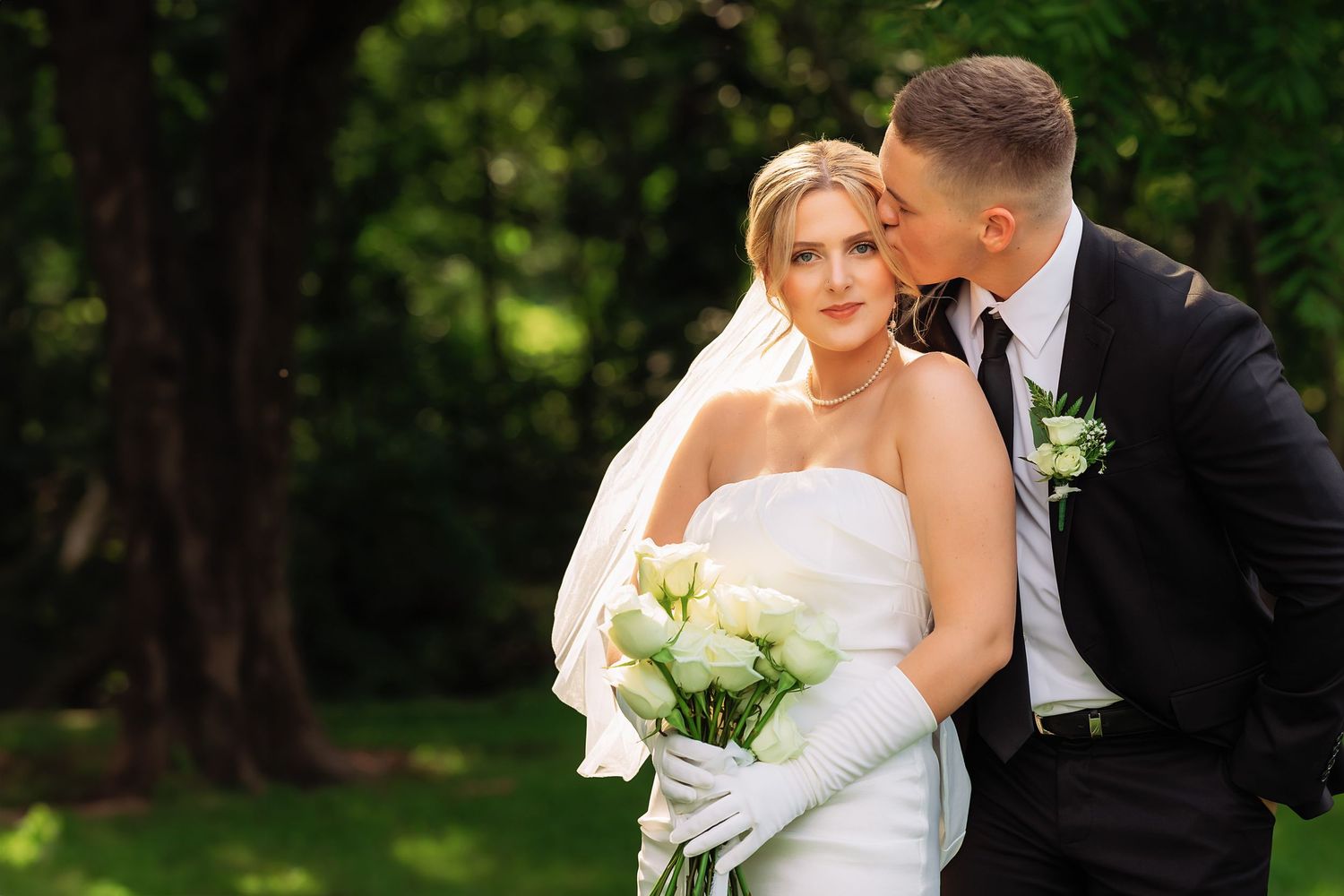 Newlyweds embracing in romantic outdoor garden setting.