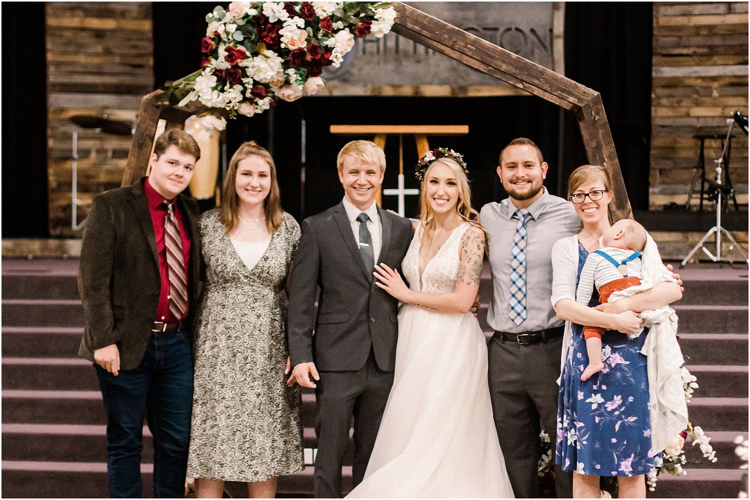 Group photo of wedding party members in formal attire standing on church steps.