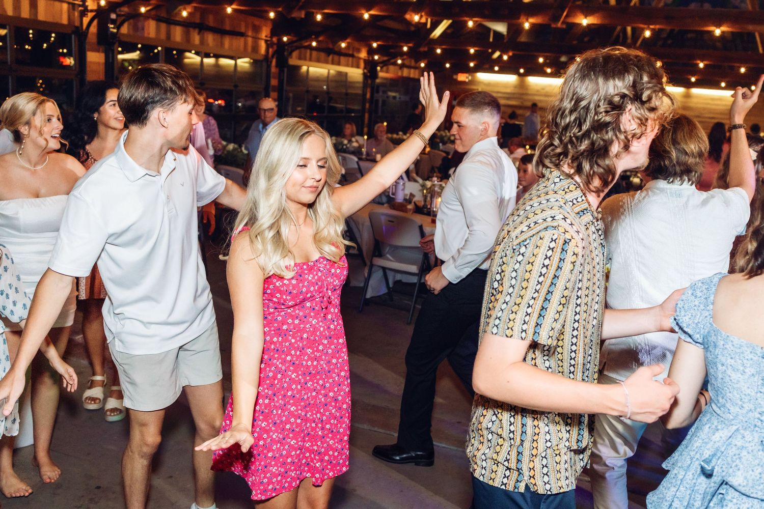 Lively wedding reception with guests dancing and celebrating on a crowded dance floor.