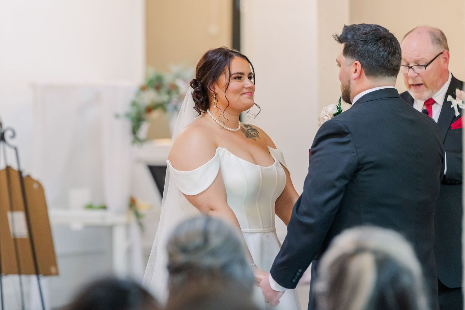 Wedding ceremony in progress with guests seated in elegant indoor venue.