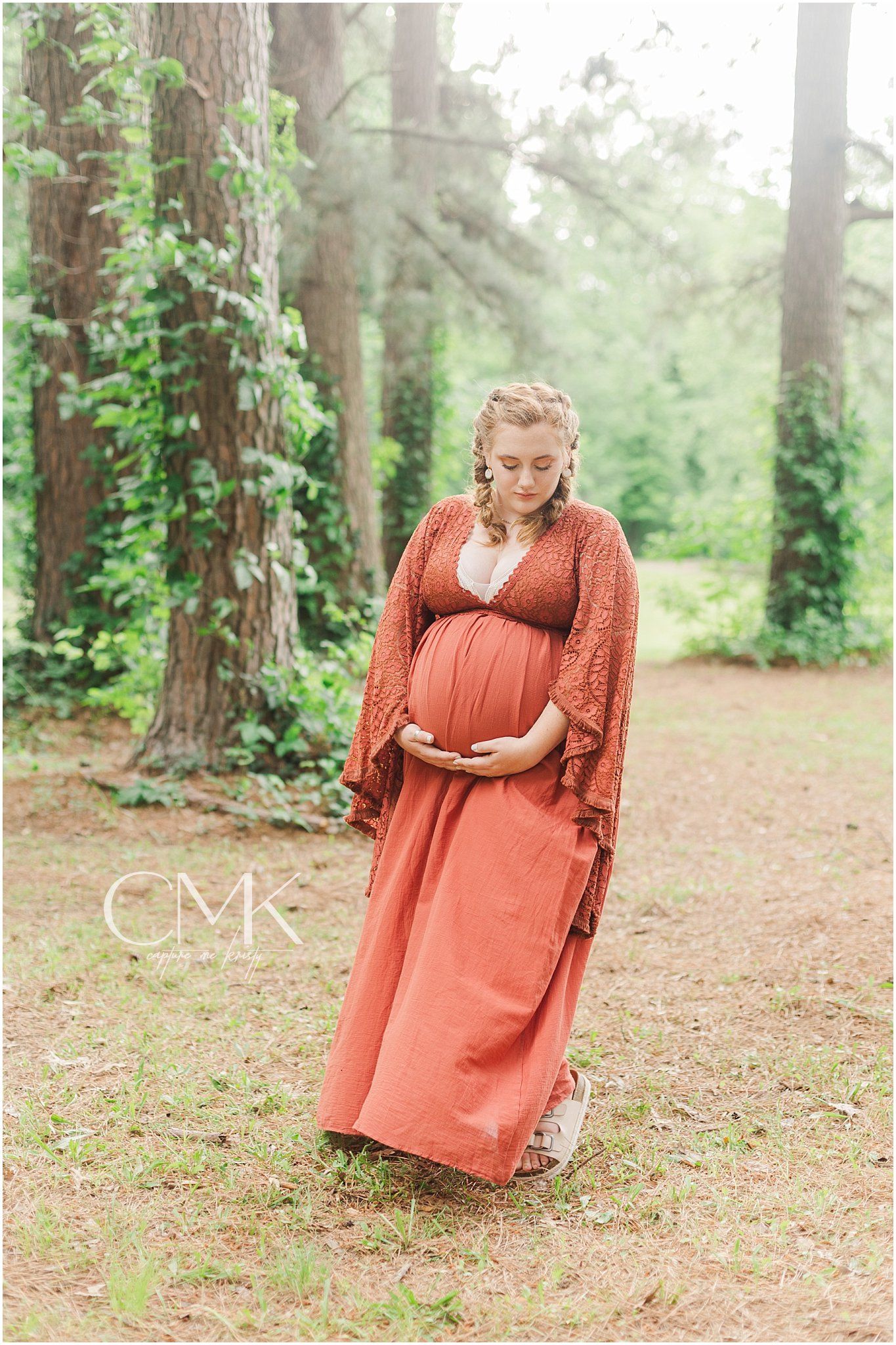 Ethereal maternity photograph in a misty forest setting with natural earth tones.
