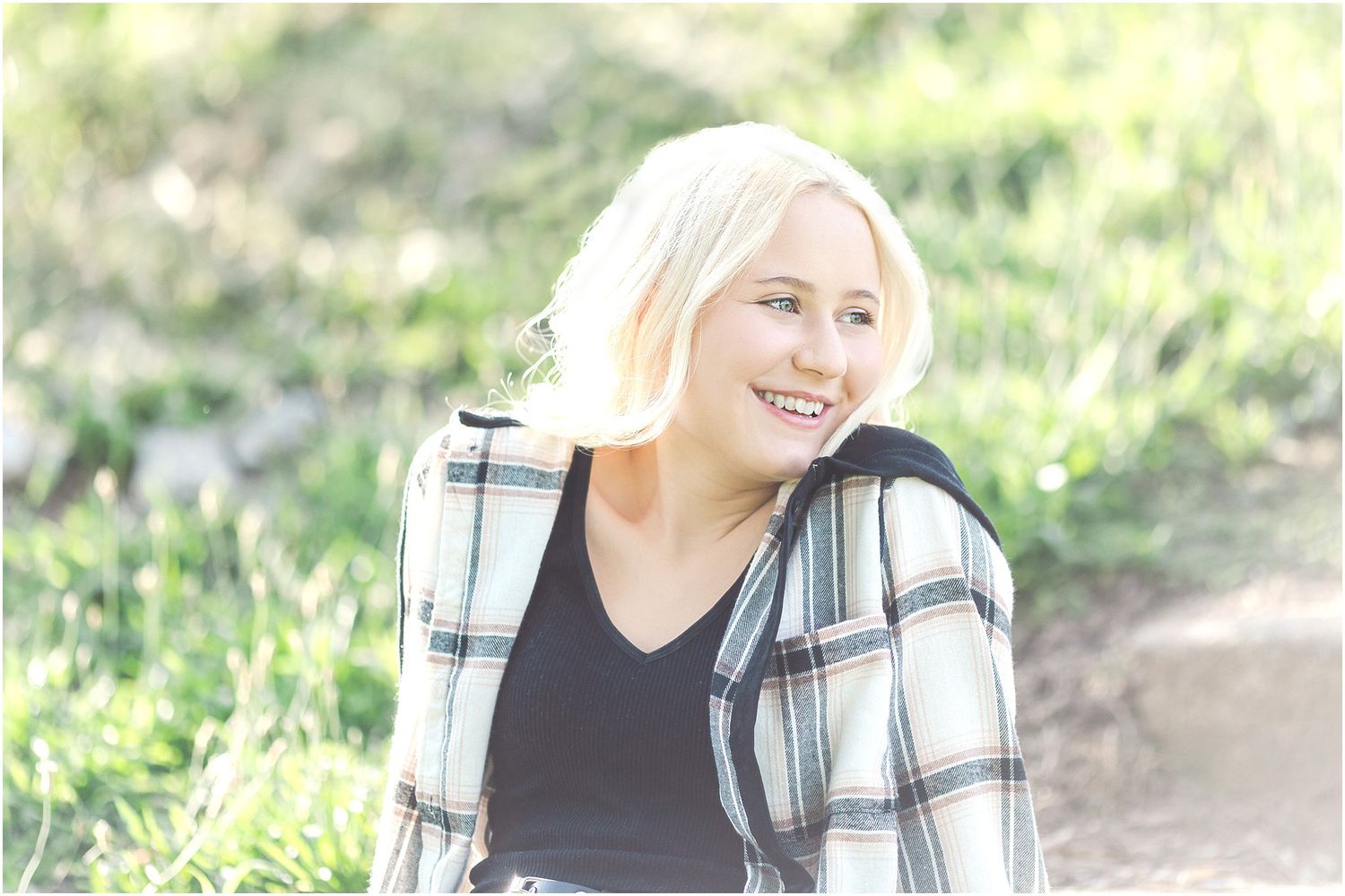 Senior girl with blonde hair looking over her shoulder smiling while sitting on steps