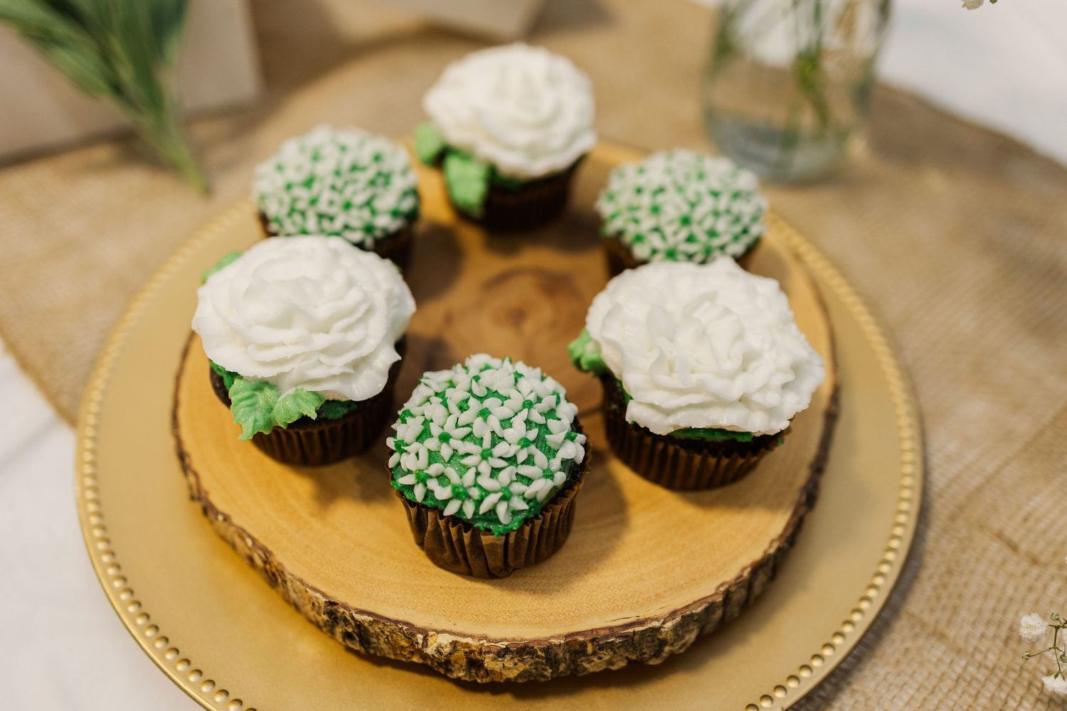 Elegant cupcakes with green and white frosting displayed on a gold serving platter.