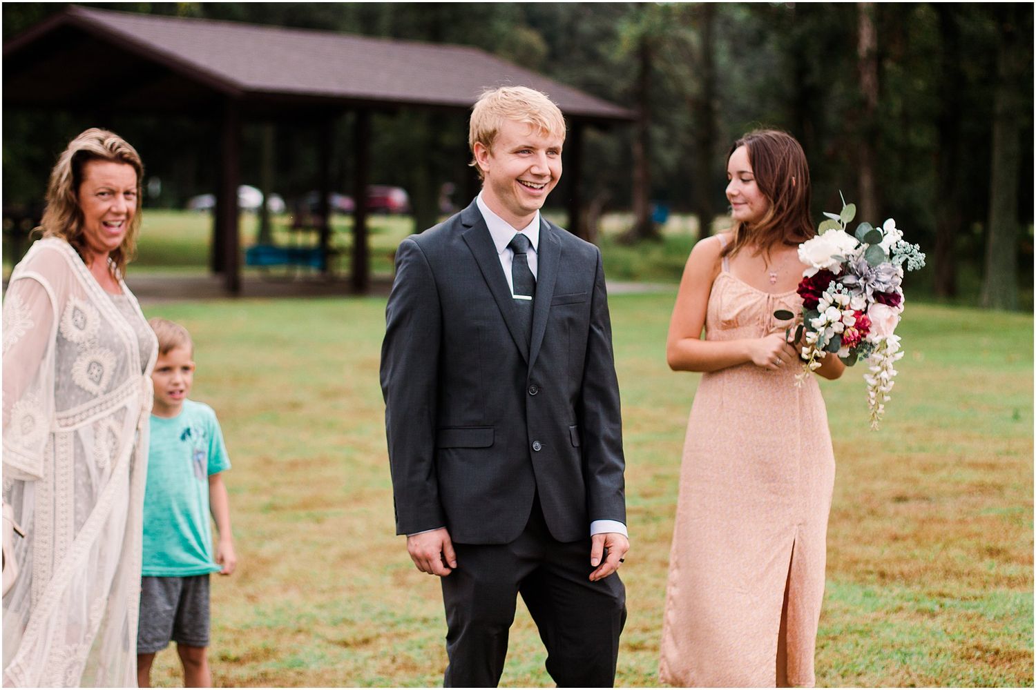 Wedding party scene outdoors with guests and attendants in casual setting.