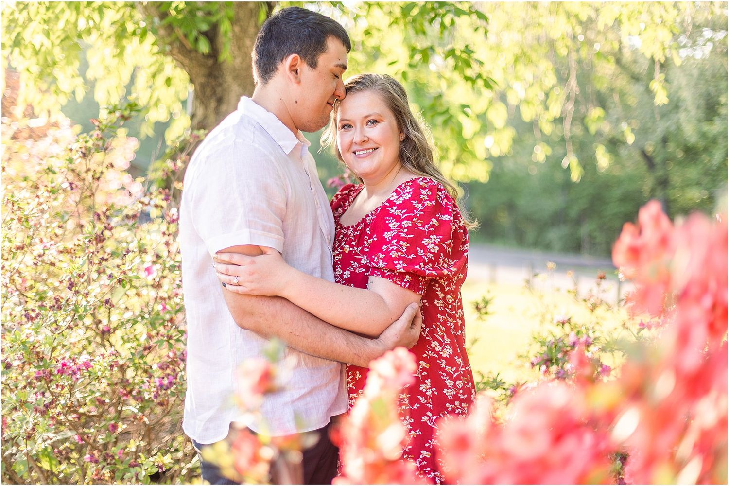 Romantic garden photoshoot with couple among blooming flowers in soft sunlight.