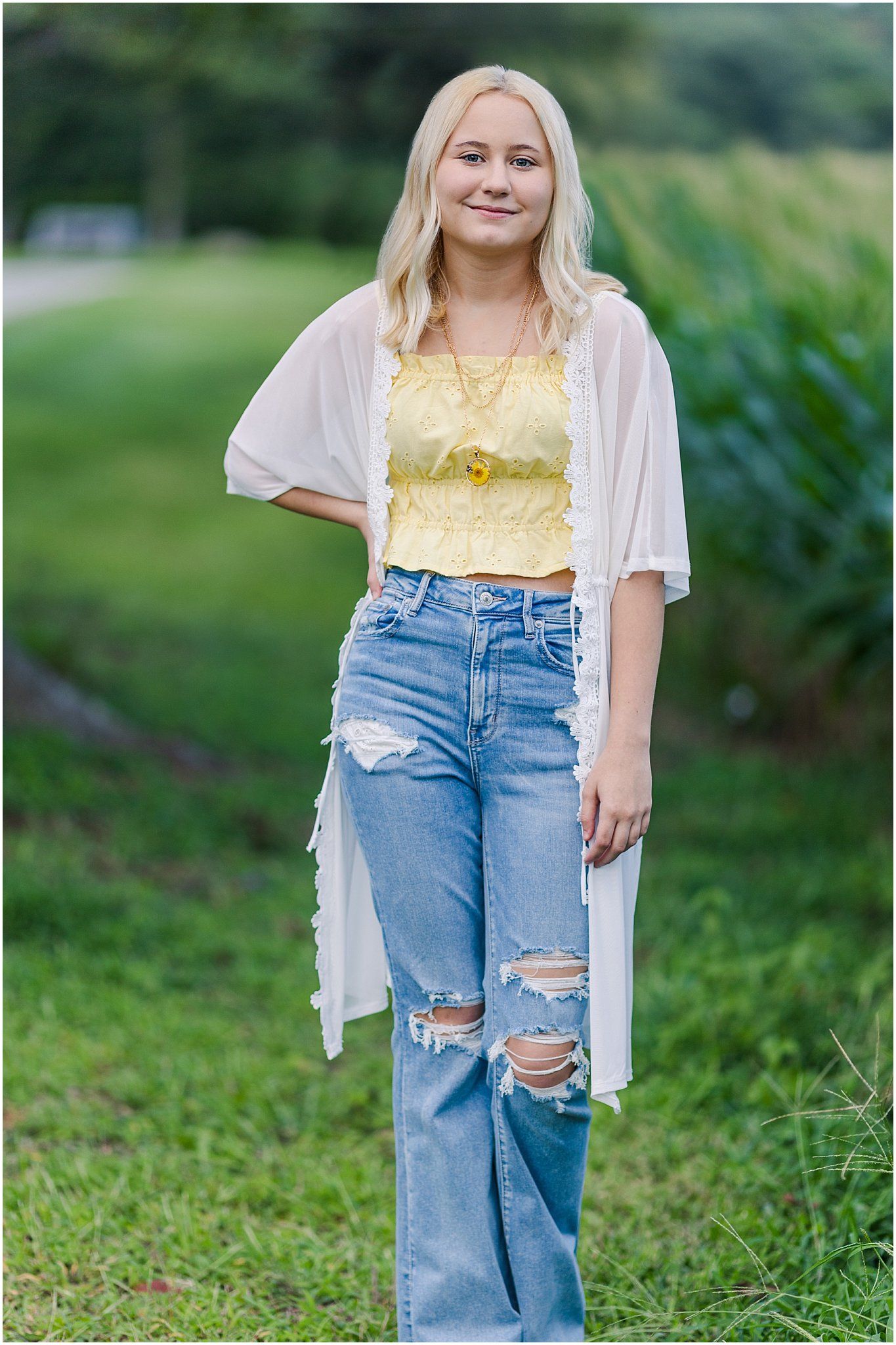 Senior girl in front of a corn field at sunset