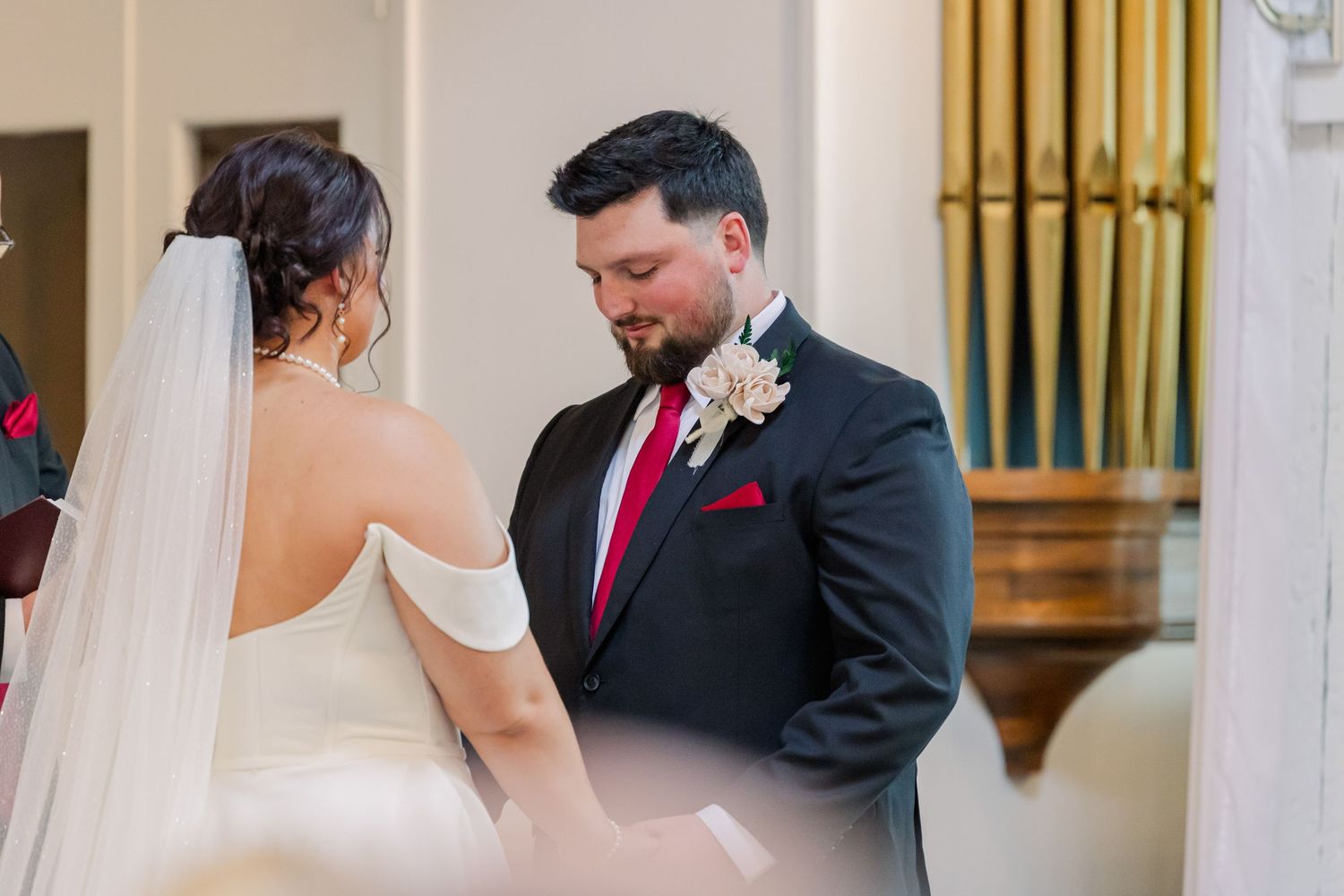 Intimate moment captured during wedding ceremony with elegant decor in background.