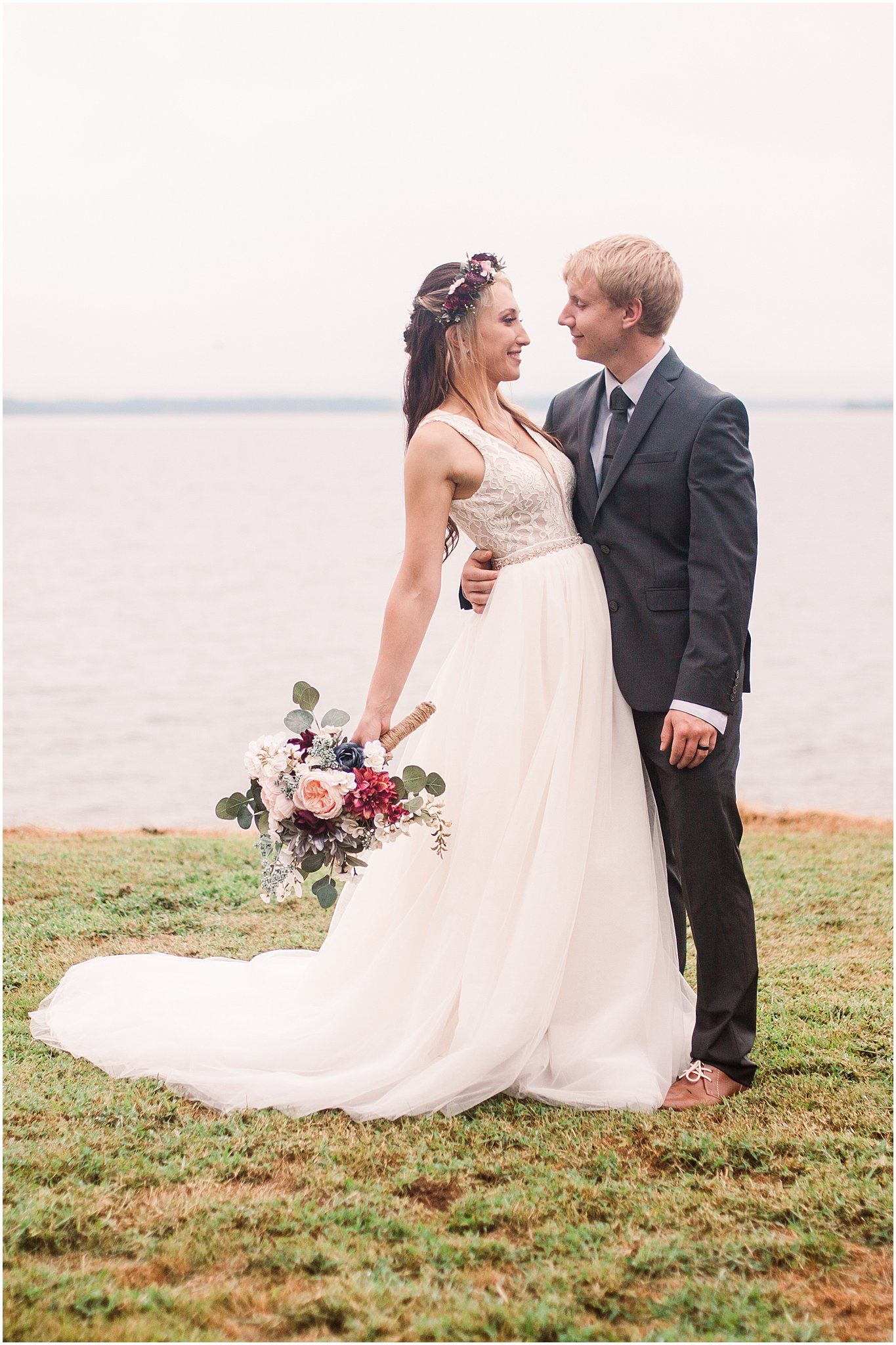 Joyful wedding couple laughing together during waterfront photo session.