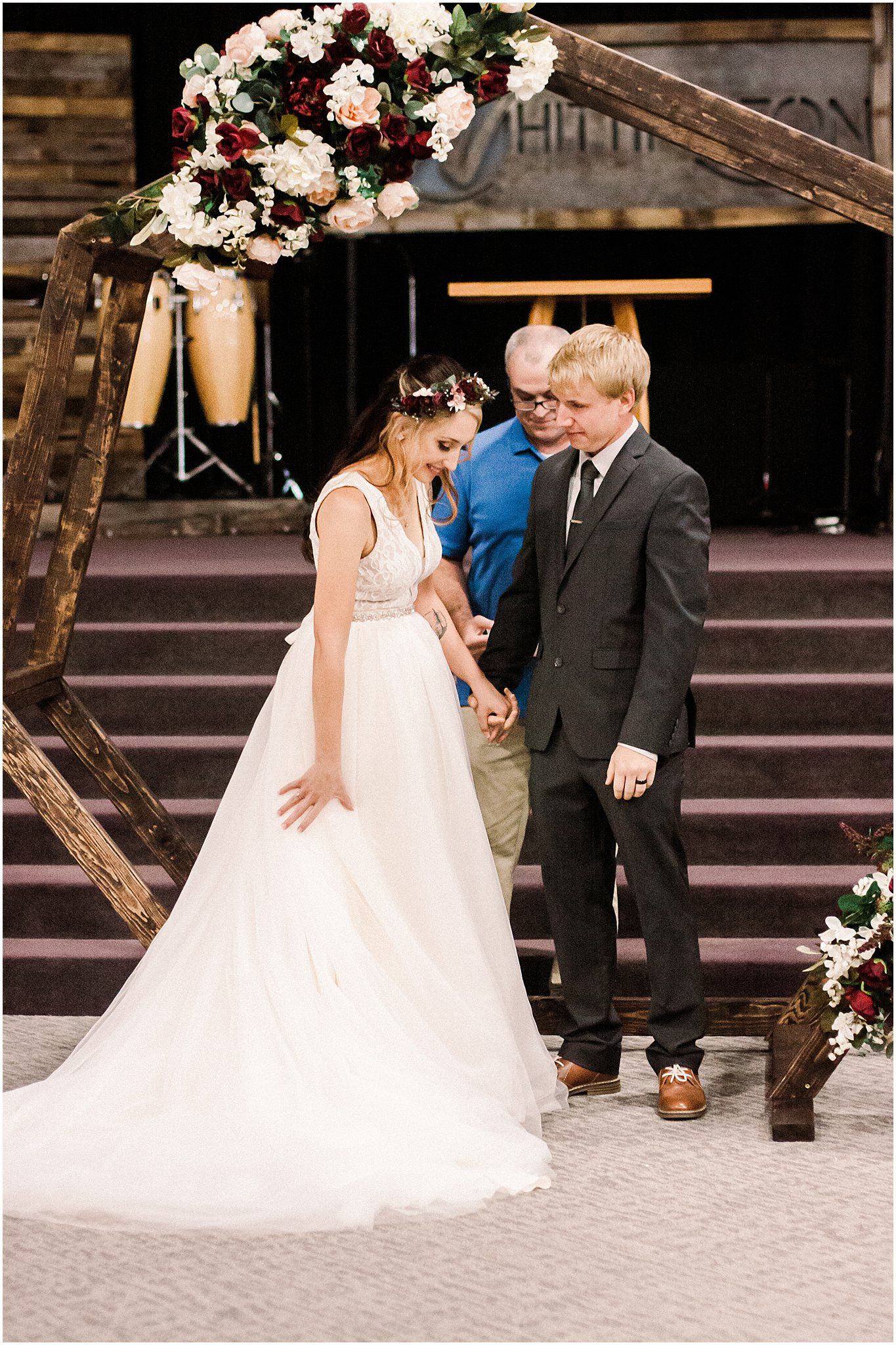 A beautiful wedding ceremony under a wooden arch decorated with pink and white flowers.