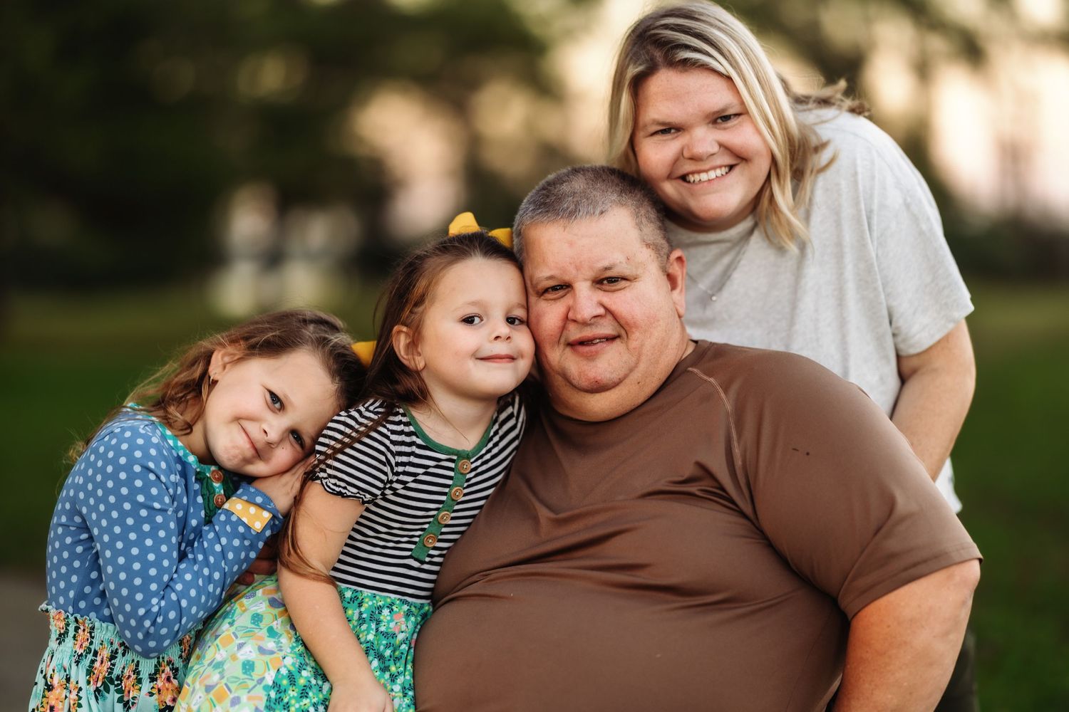 Casual outdoor family portrait session with everyone embracing and smiling together.