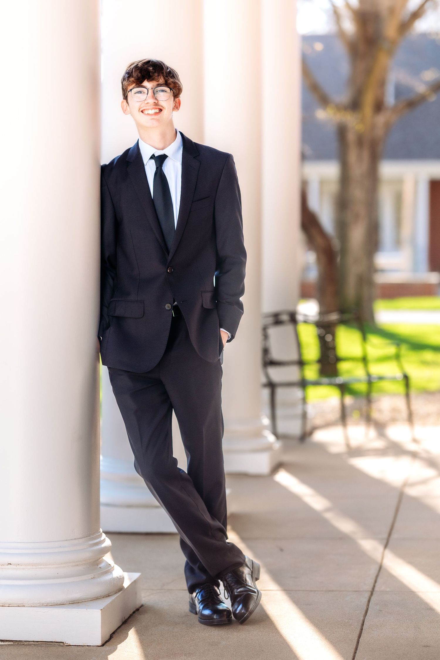 A series of formal portraits taken in a bright colonnade with white pillars and sunlit walkway.
