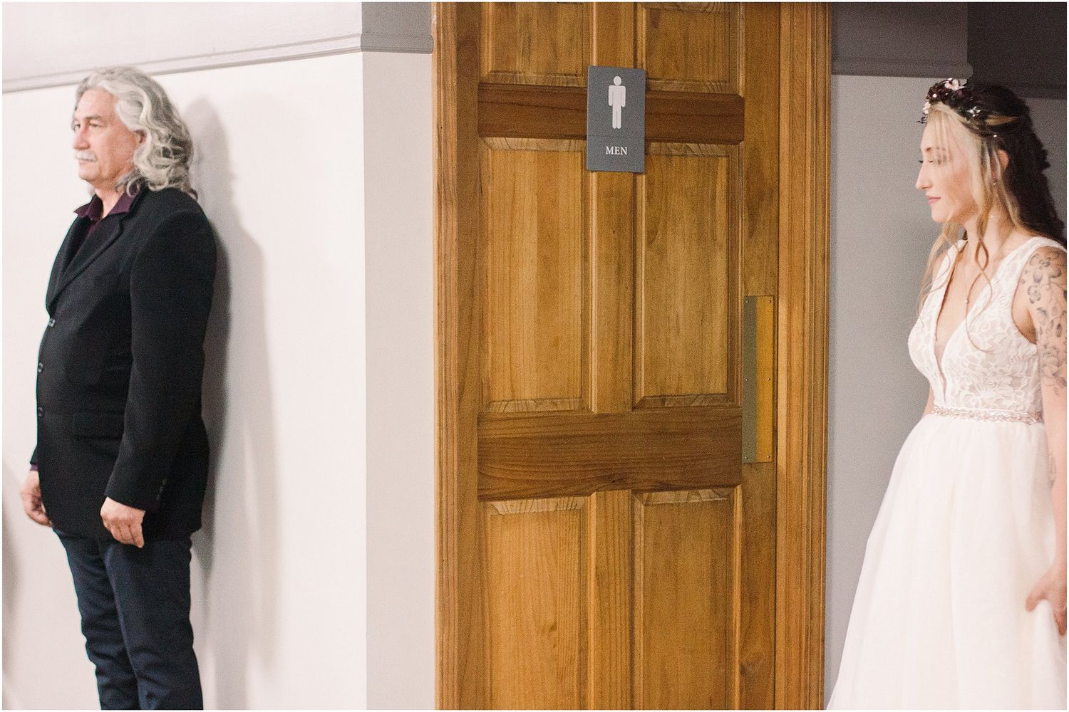 A first look wedding moment captured through a wooden doorway with dramatic lighting.