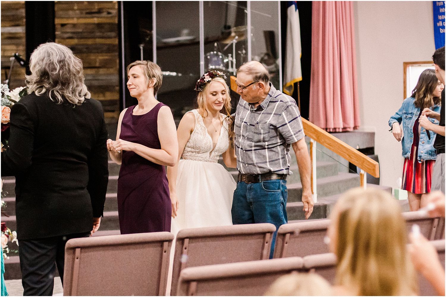 Wedding celebration with guests in casual and formal attire interacting at a venue entrance.